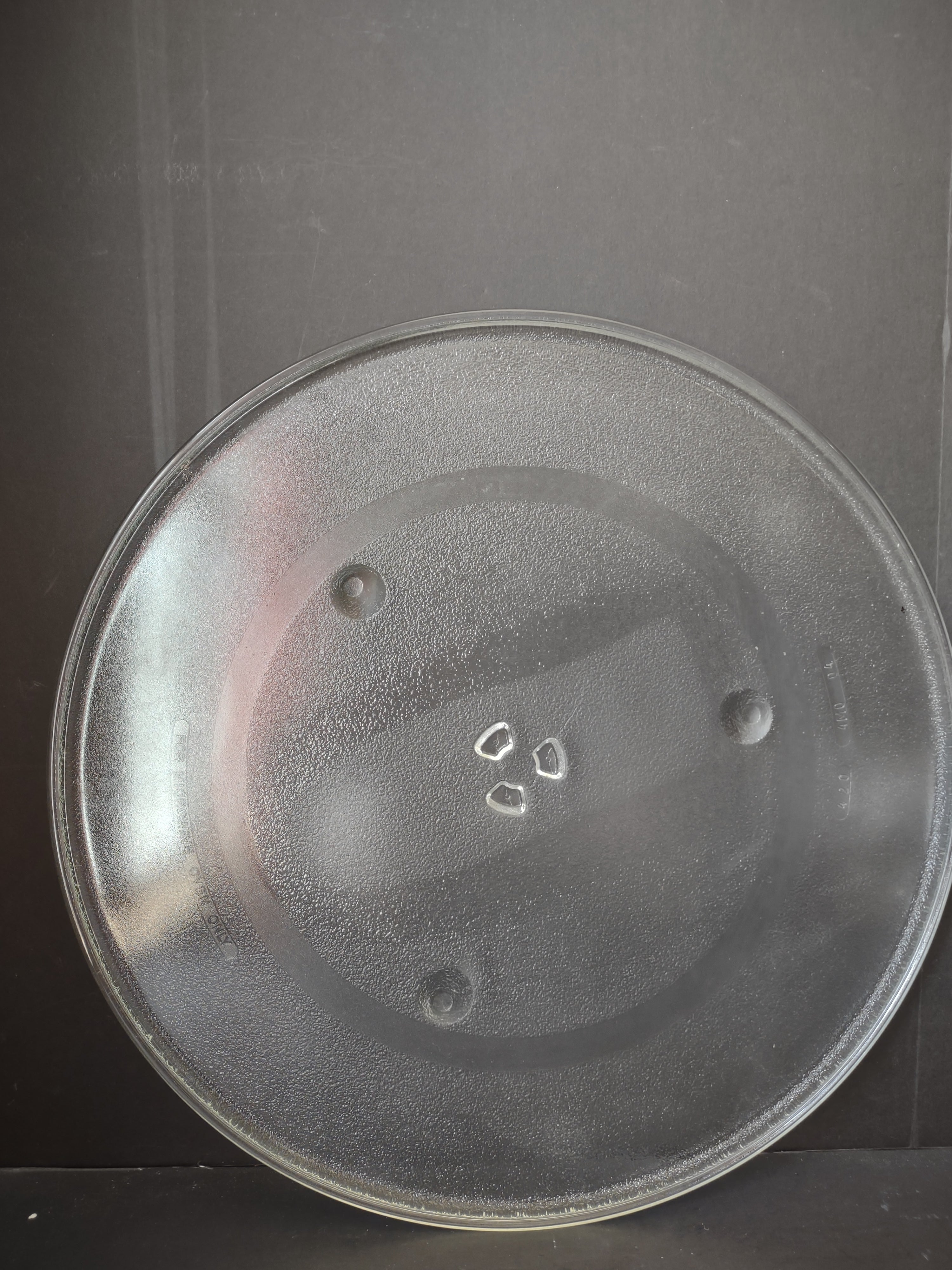 Vintage clear glass microwave turntable plate, front view showing textured surface and concentric rings