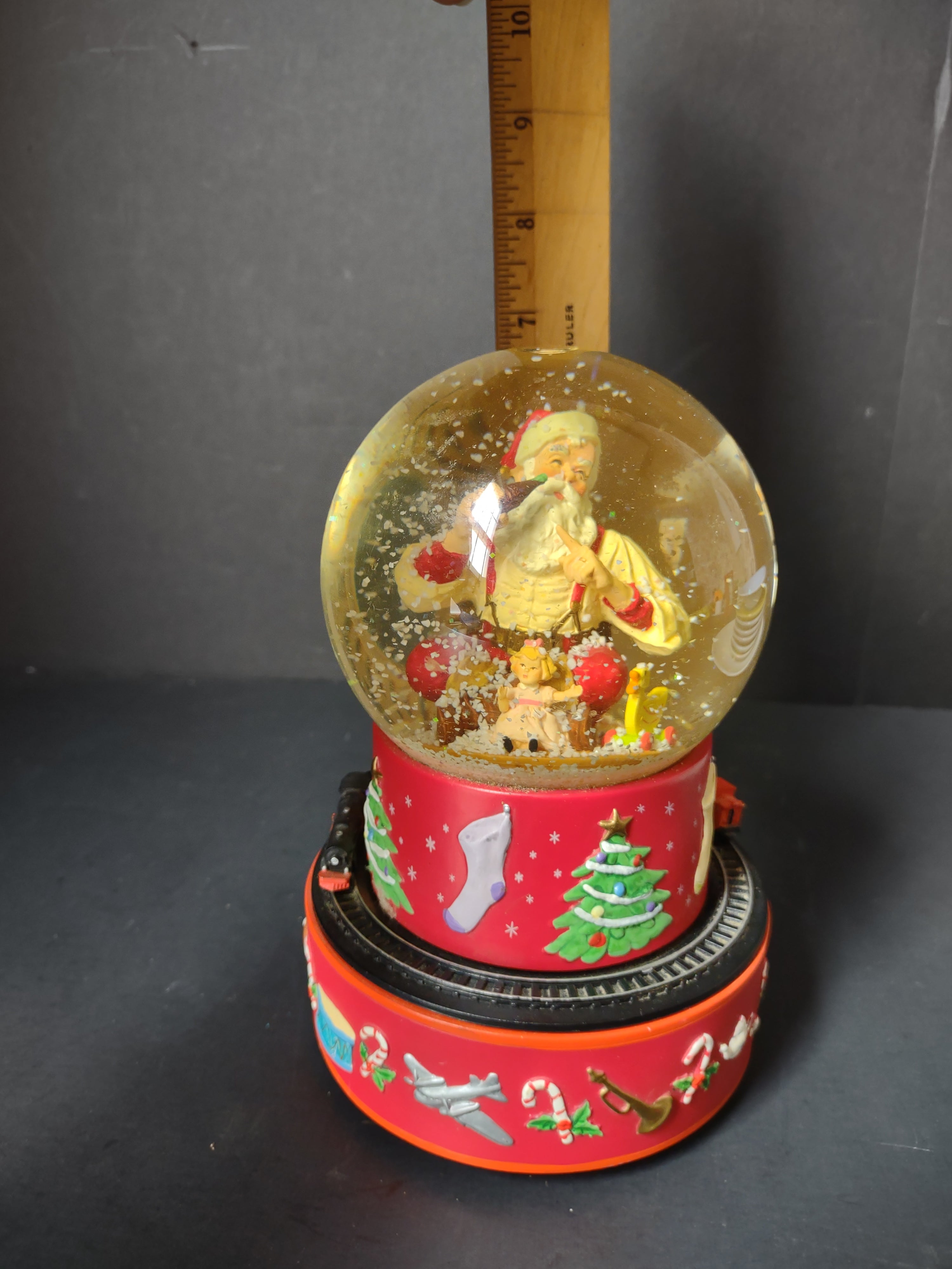 Vintage Coca-Cola Hallmark musical snow globe base close-up showing Christmas motifs including airplane candy canes and horn