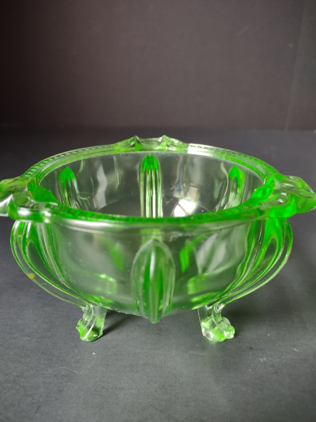 Vintage green uranium glass footed bowl angled view under UV black light