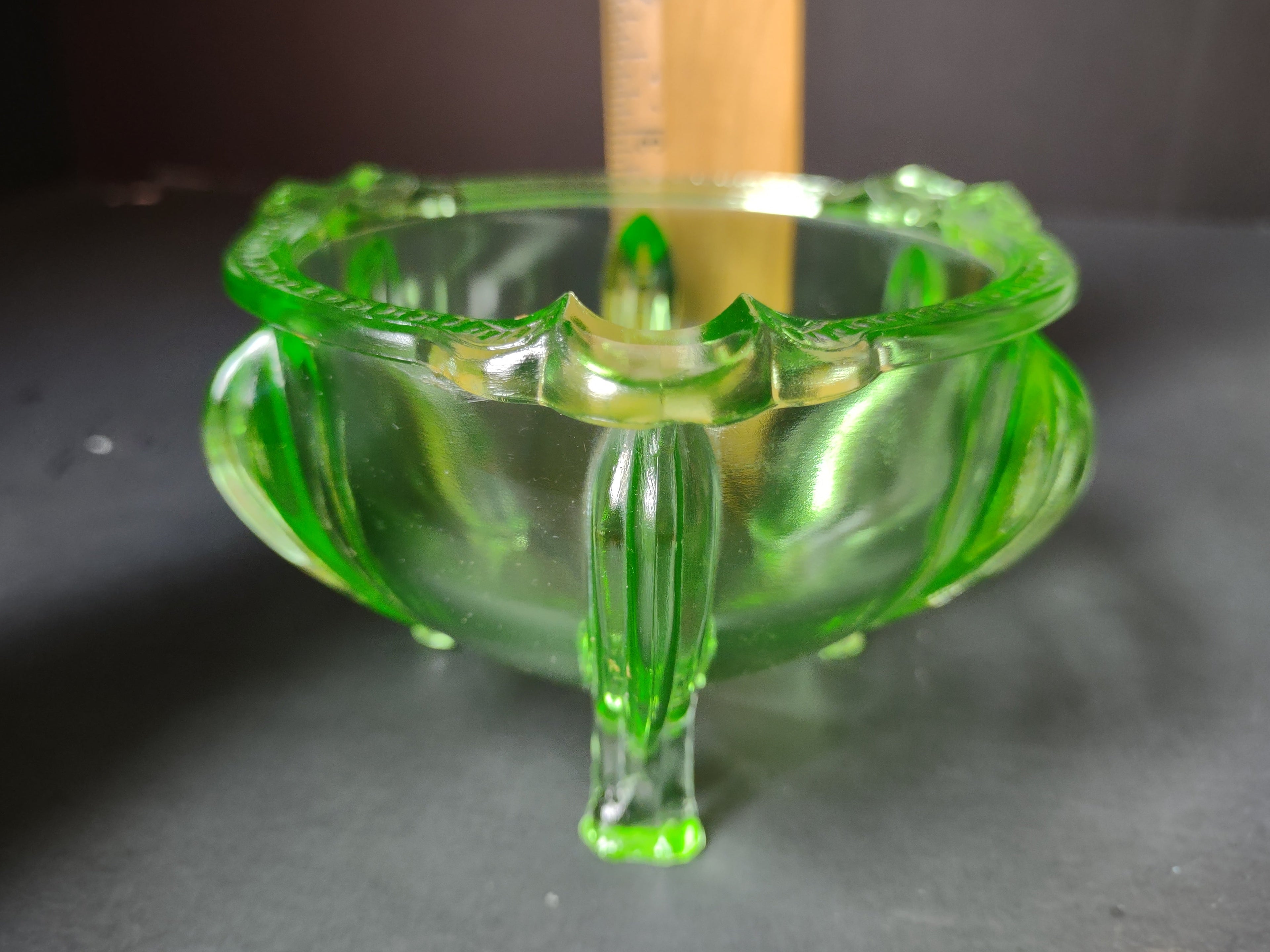 Vintage green uranium glass footed bowl close-up of rim showing chip damage