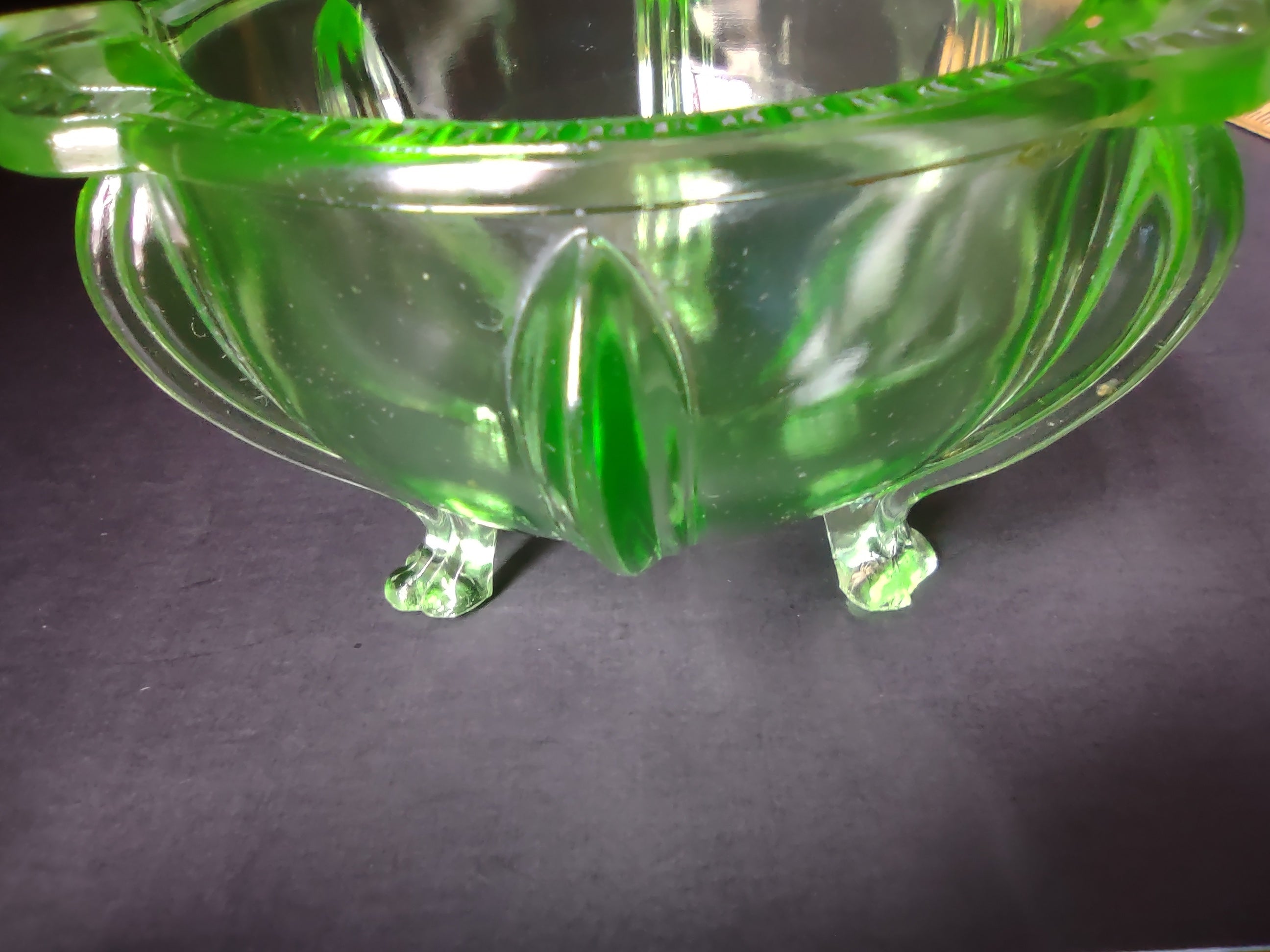Vintage green uranium glass footed bowl side view showing tulip feet and vertical ribbing