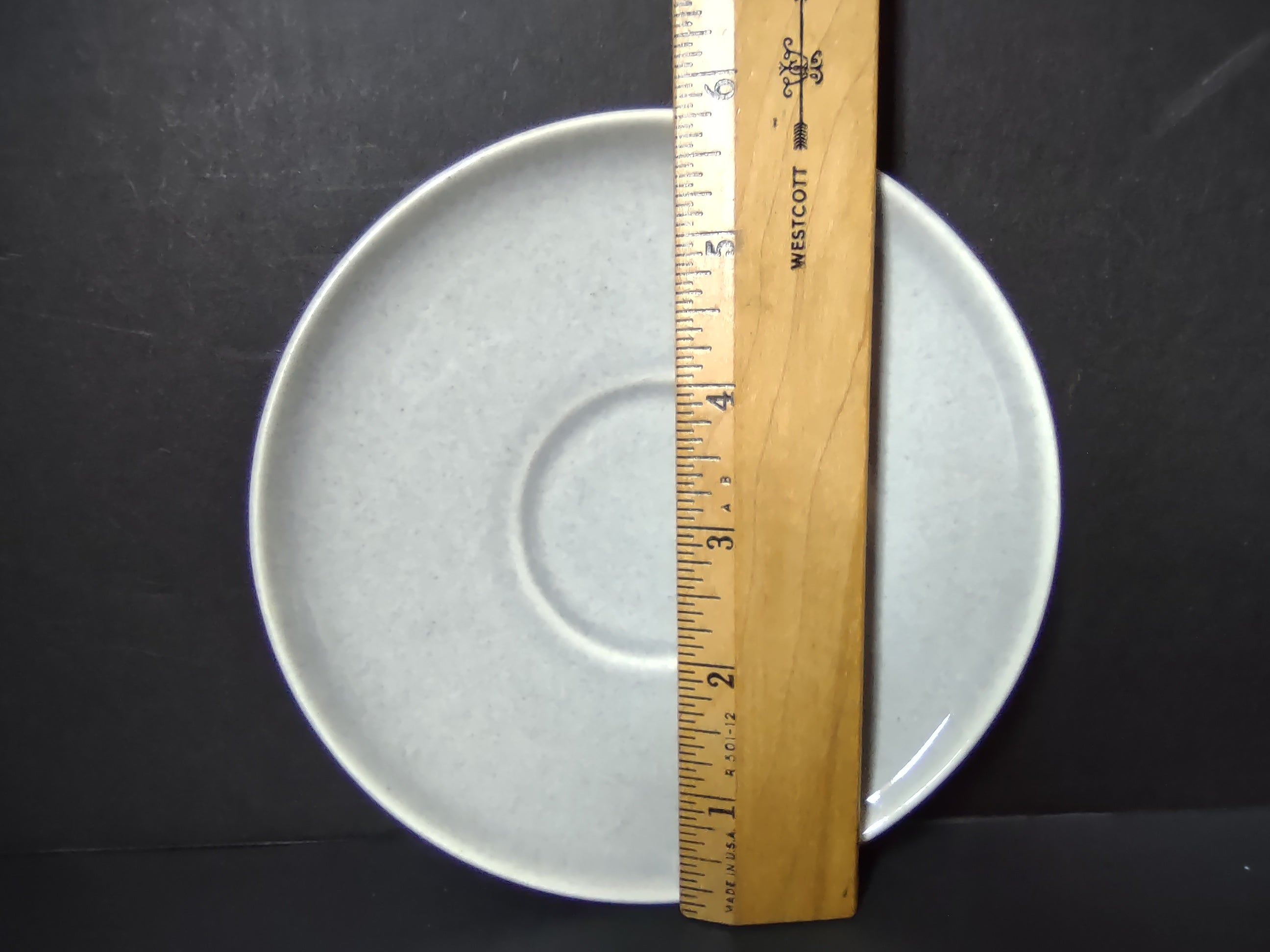 Vintage white unbranded saucer front view showing plain off-white glaze and cup well