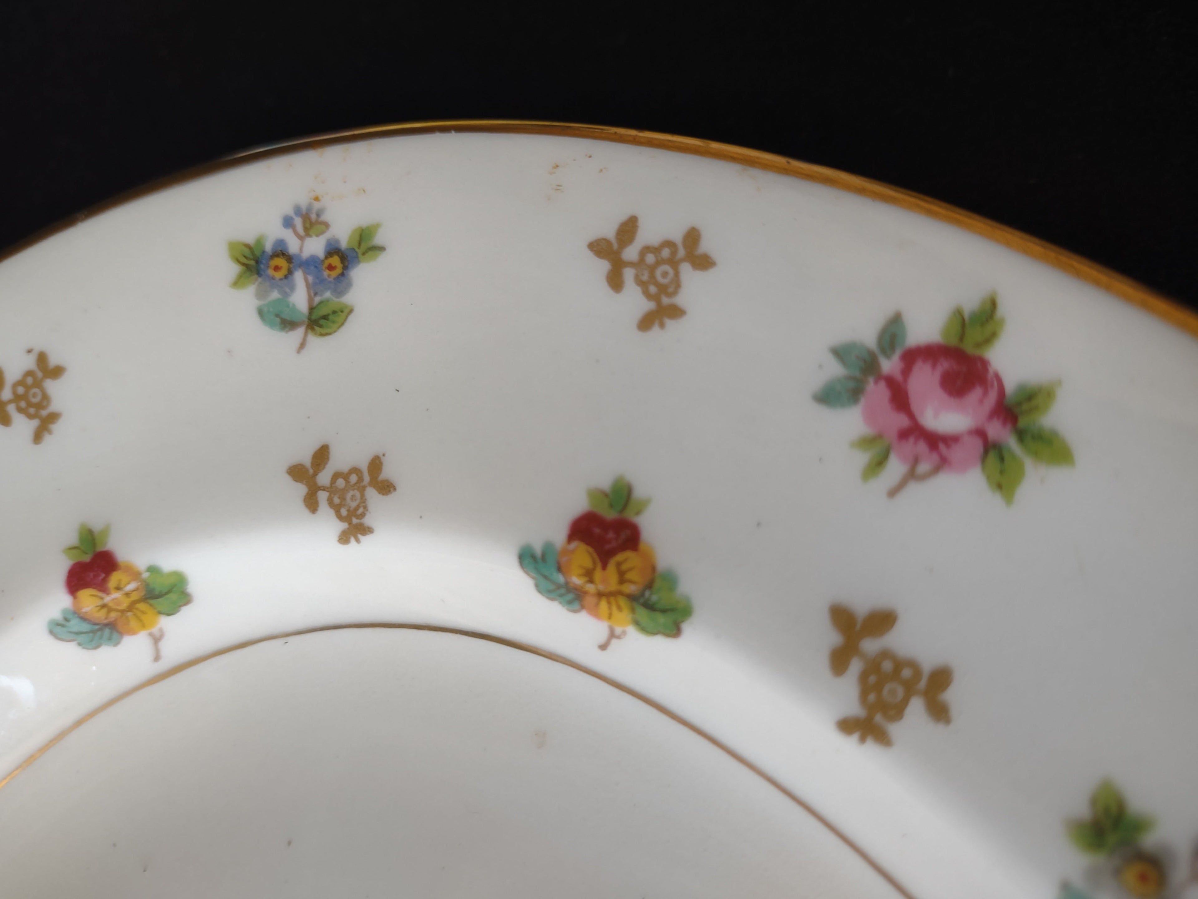 Close-up of scattered floral pattern — pink roses, pansies, forget-me-nots, gold motifs