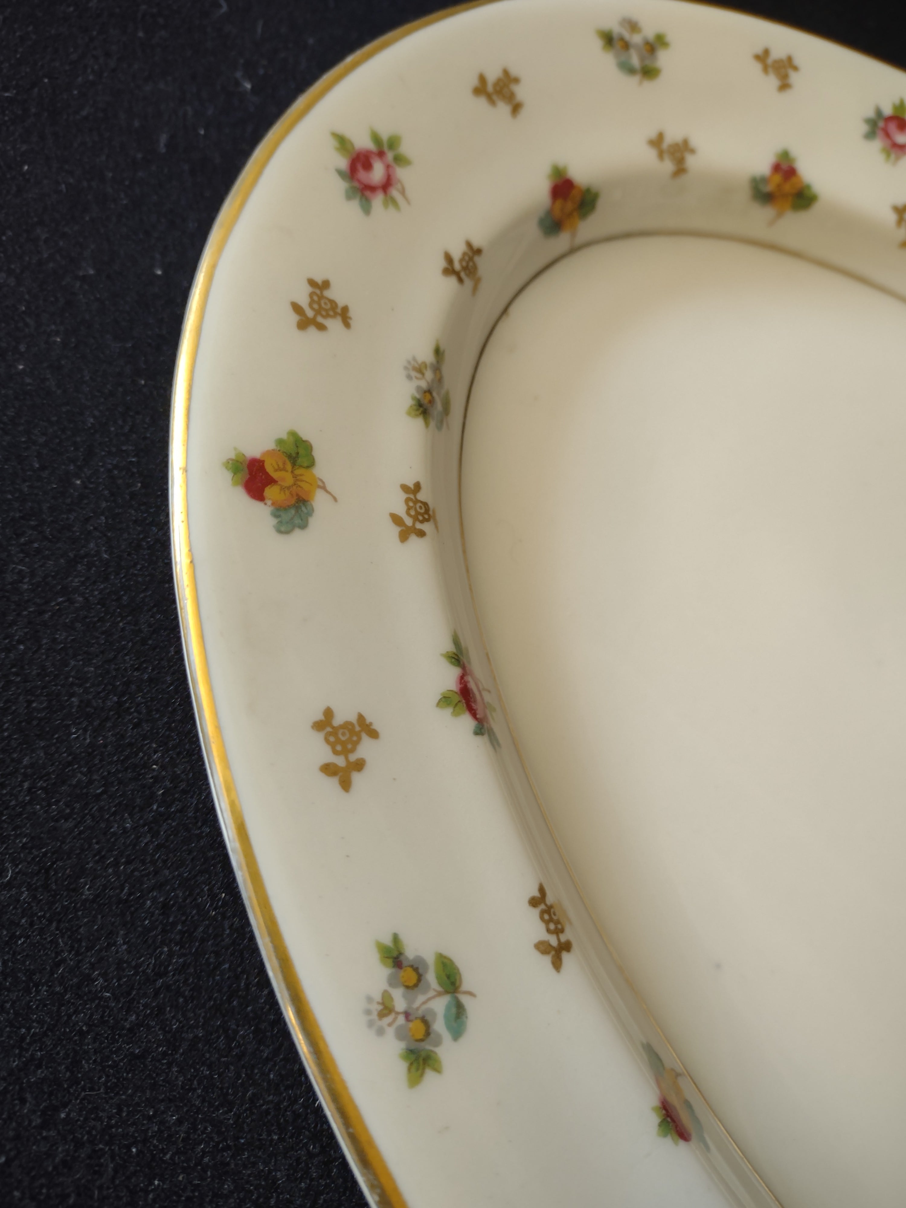 Corner detail showing floral sprigs and gold rim