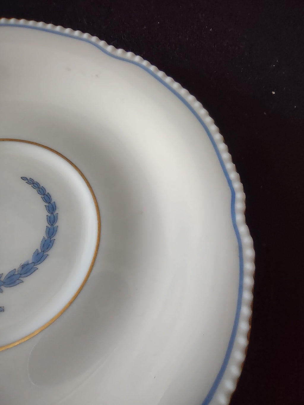 Close-up of saucer center with blue laurel wreath and gold ring