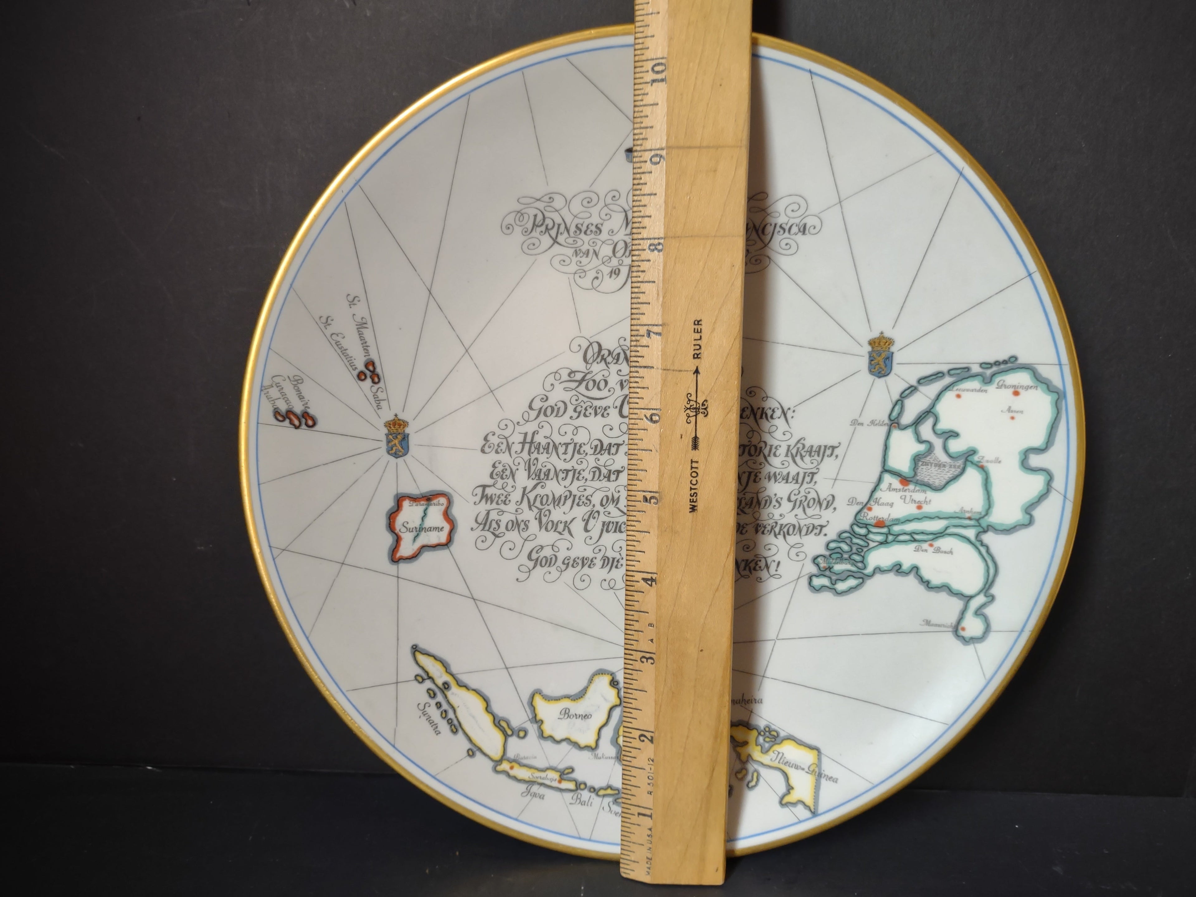 Front view of Netherlands Aid Society commemorative plate showing Dutch maps, calligraphic poem, and gold rim