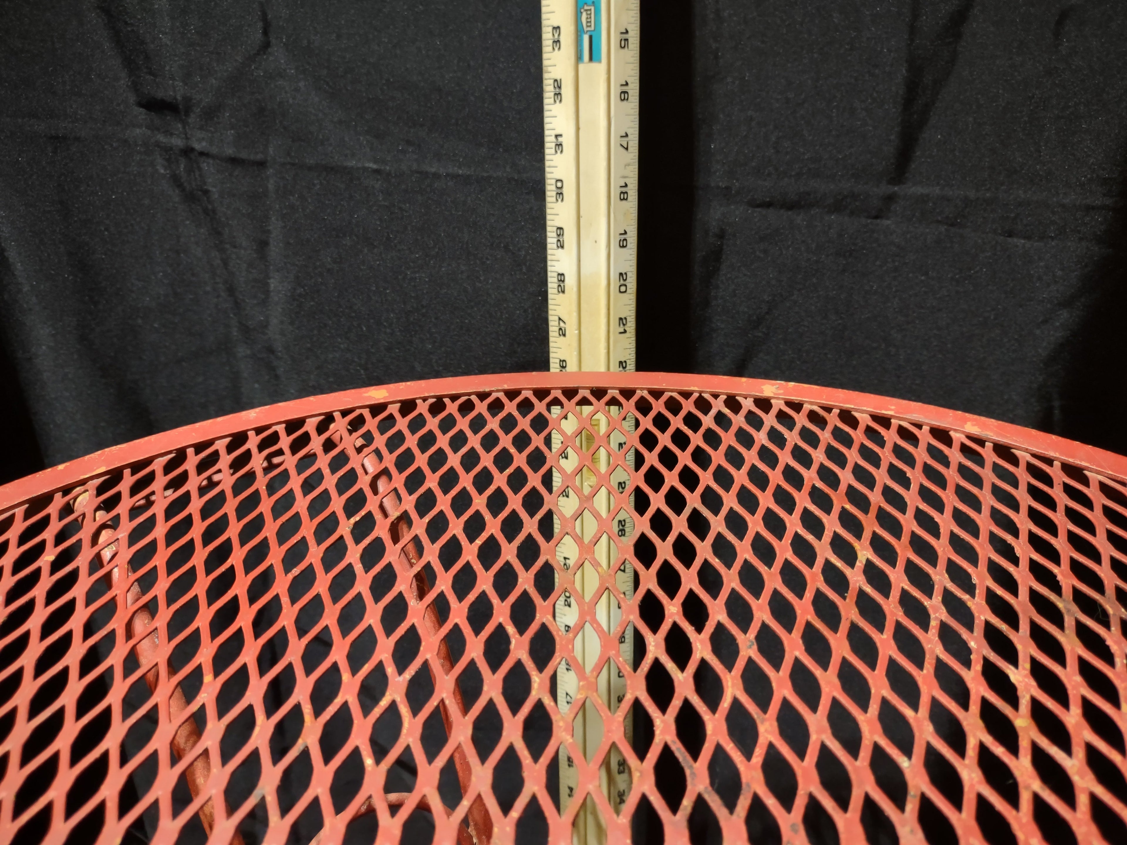 Vintage red metal mesh bistro table - tabletop edge with ruler showing approximately 30 inch diameter