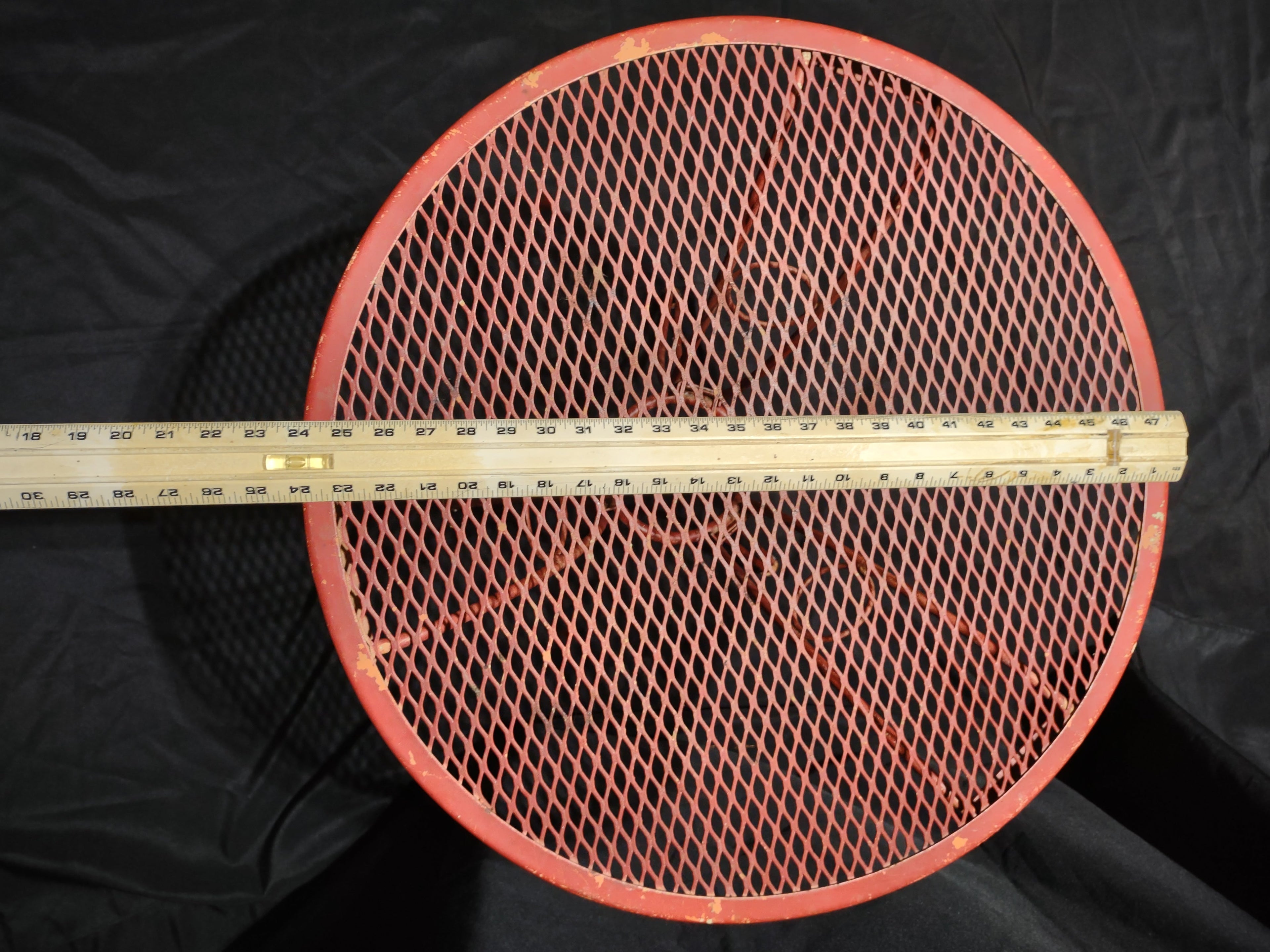Vintage red metal mesh bistro table - underside view showing pedestal base and center ring brace