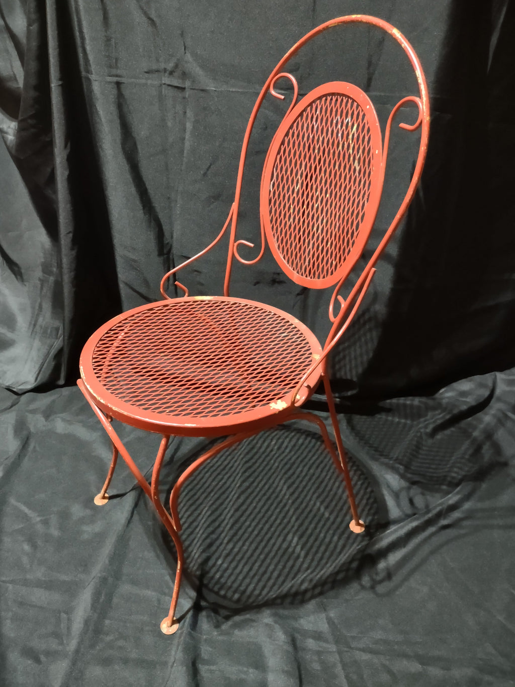 Vintage red metal mesh bistro chair - top-down view showing round mesh seat and scrollwork back