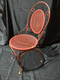 Vintage red metal mesh bistro chair - top-down view showing round mesh seat and scrollwork back
