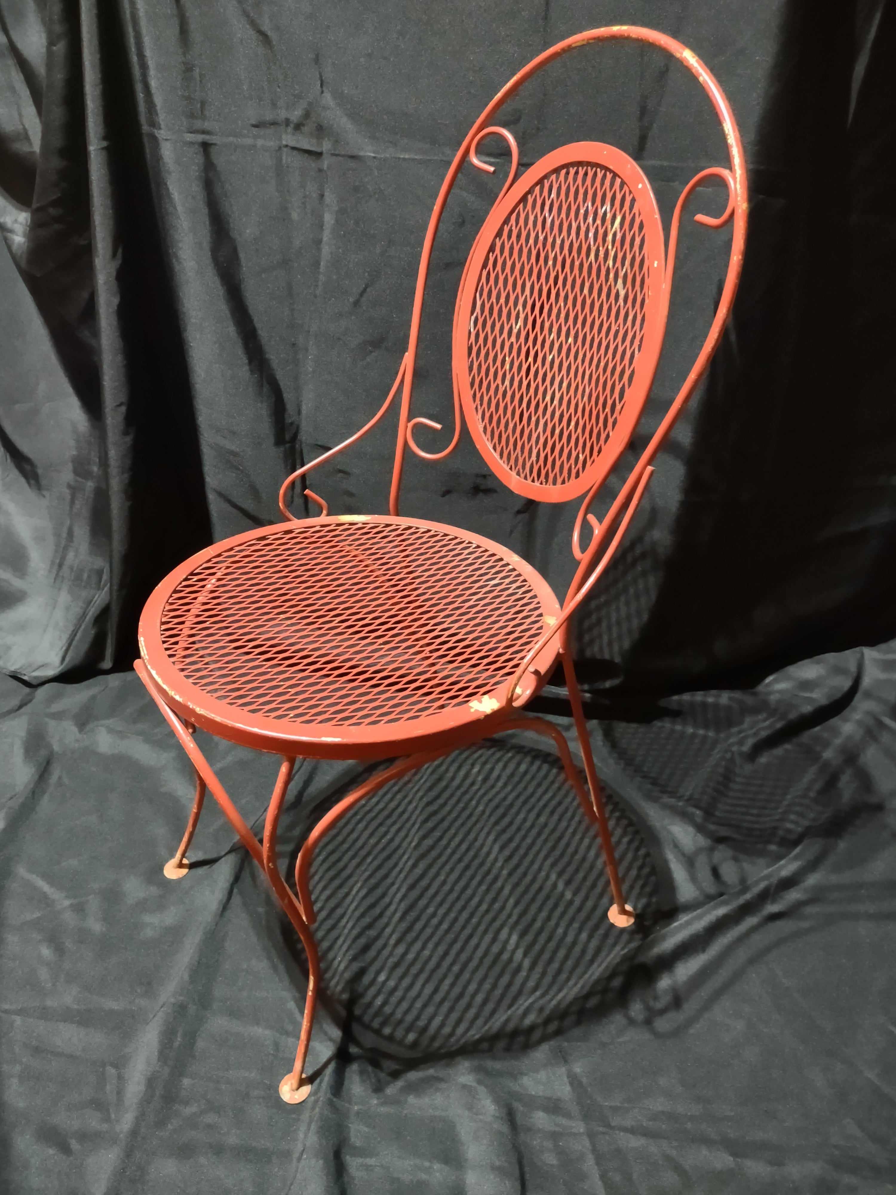 Vintage red metal mesh bistro chair - top-down view showing round mesh seat and scrollwork back
