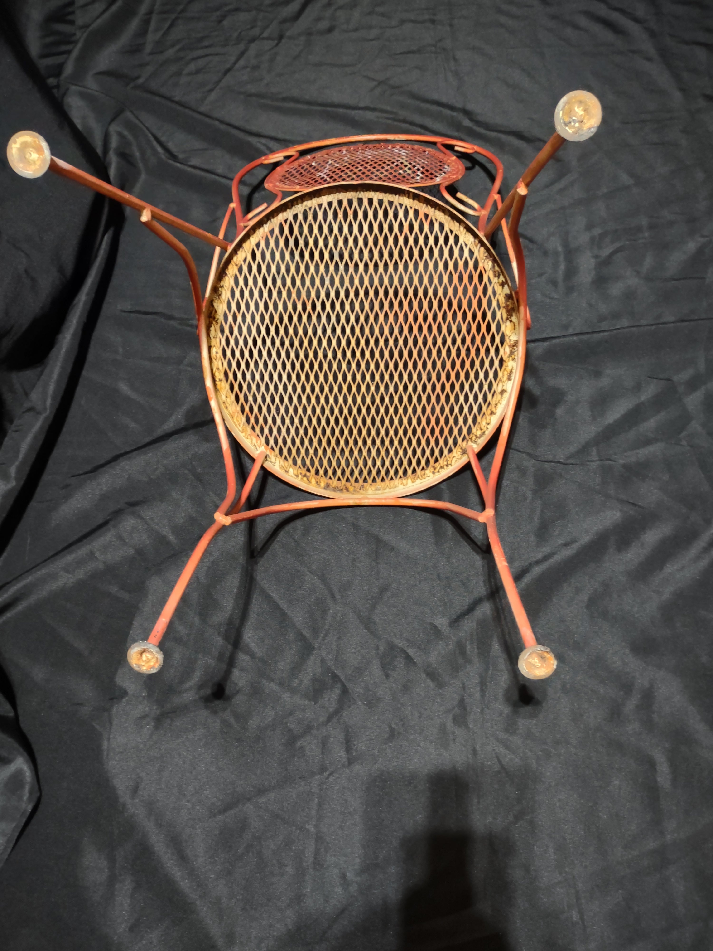Vintage red metal mesh bistro chair - front view showing scrollwork back and round seat