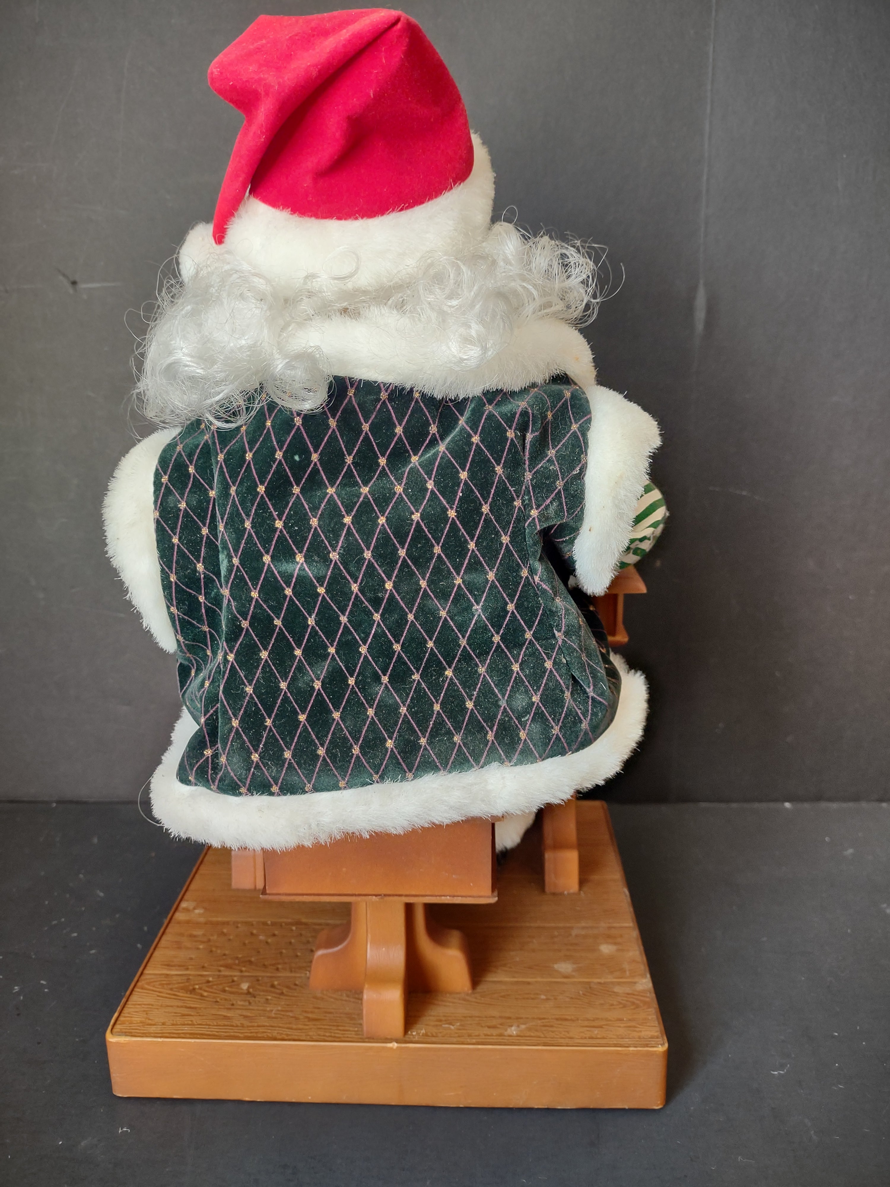 Vintage animated Santa Claus seated at school desk - front view showing face, glasses, and green velvet coat