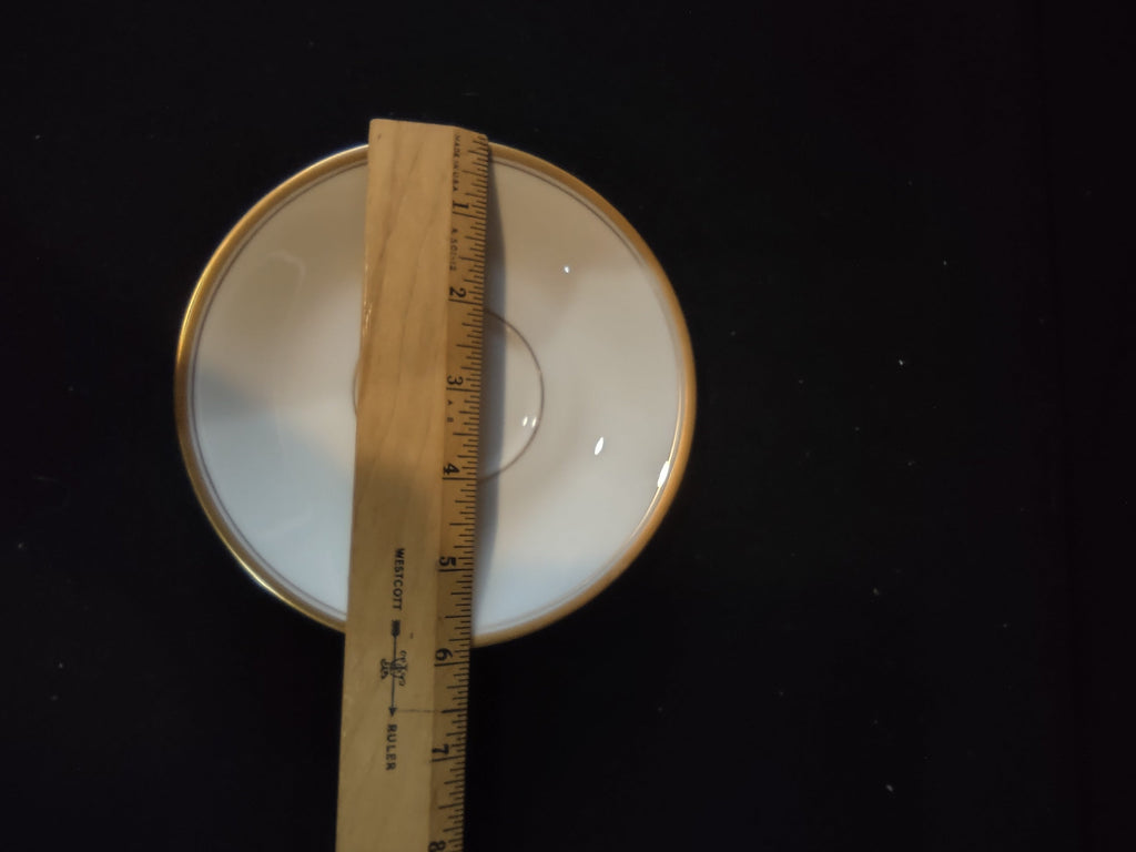 Vintage Syracuse China Regent pattern saucer with ruler showing approximately 5 inch diameter, plain white porcelain with gold band rim