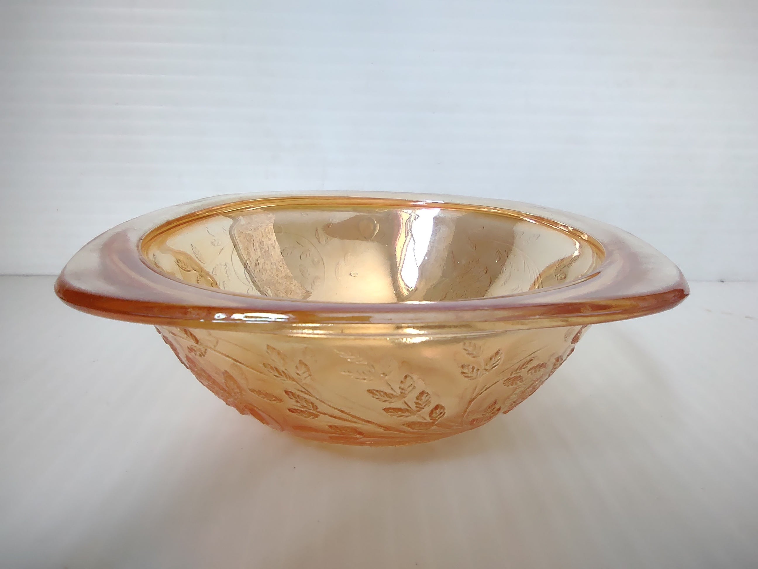 Side view of vintage marigold carnival glass square bowl with embossed grape leaf and berry pattern