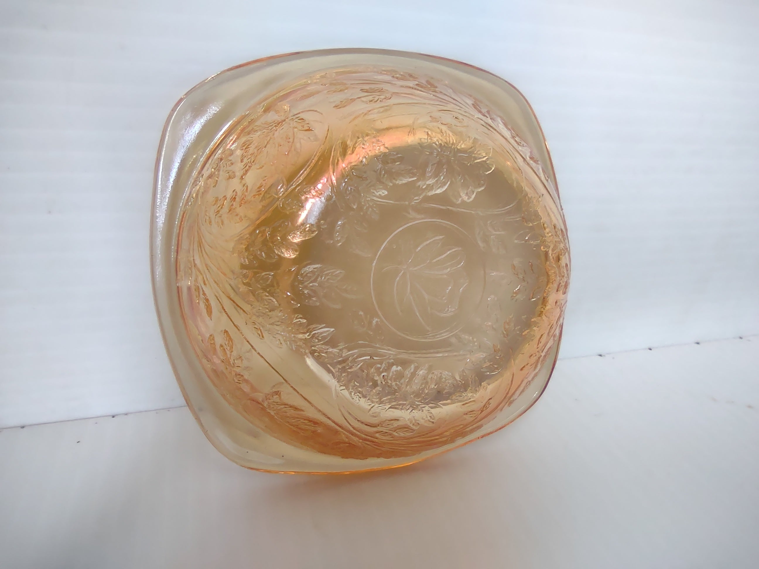 Top-down view of marigold carnival glass square bowl showing grape leaf pattern and central clover medallion