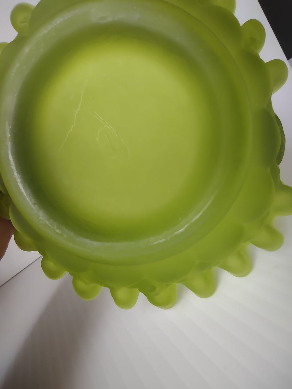Base of lime green satin glass hobnail basket showing no maker's mark and scratch on interior