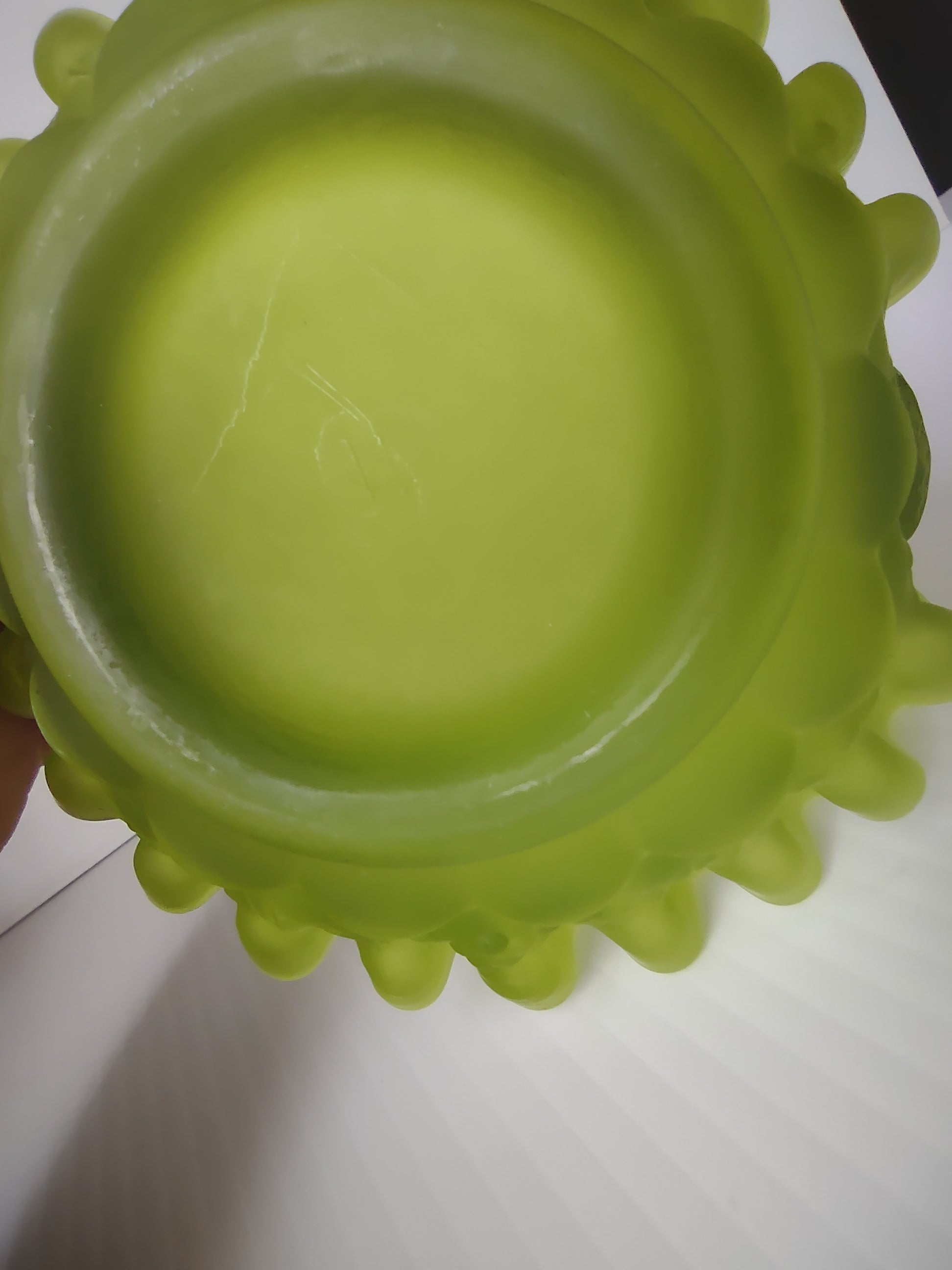 Base of lime green satin glass hobnail basket showing no maker's mark and scratch on interior