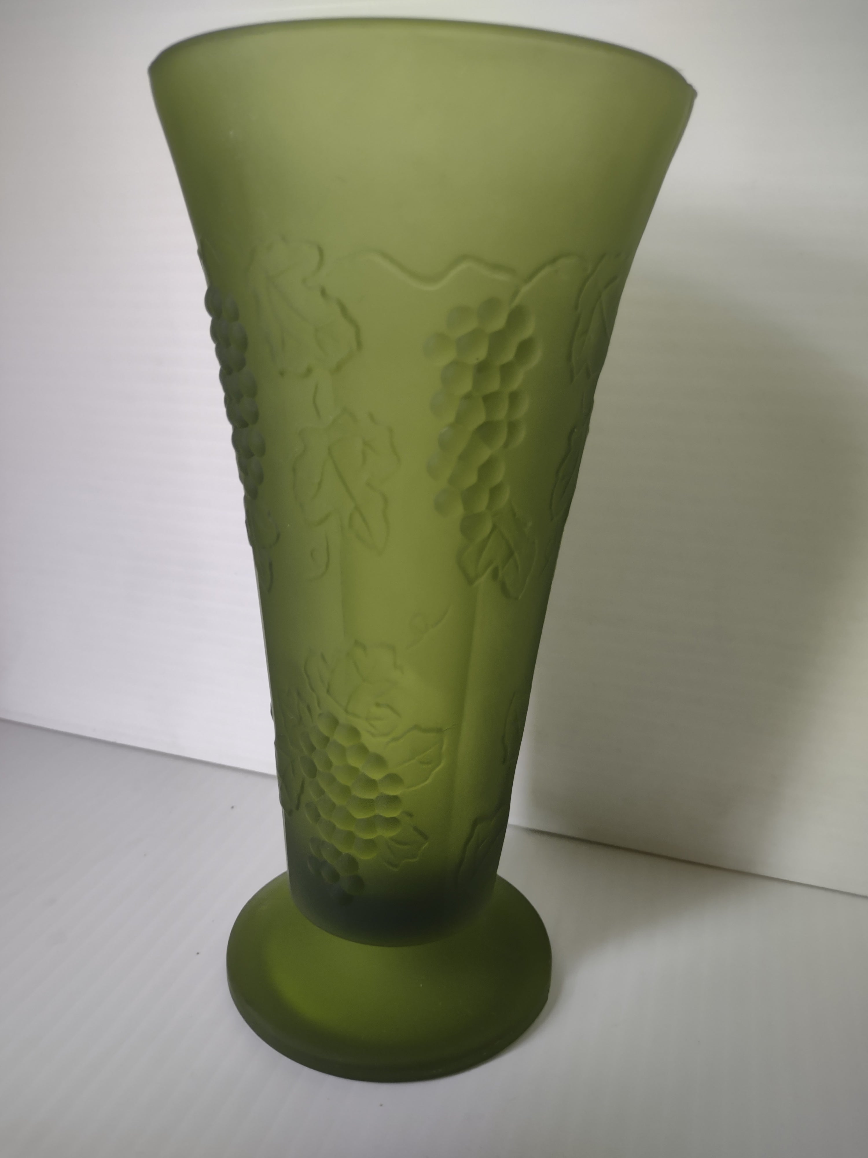 Full view of olive green satin glass footed trumpet vase showing embossed grape vine decoration