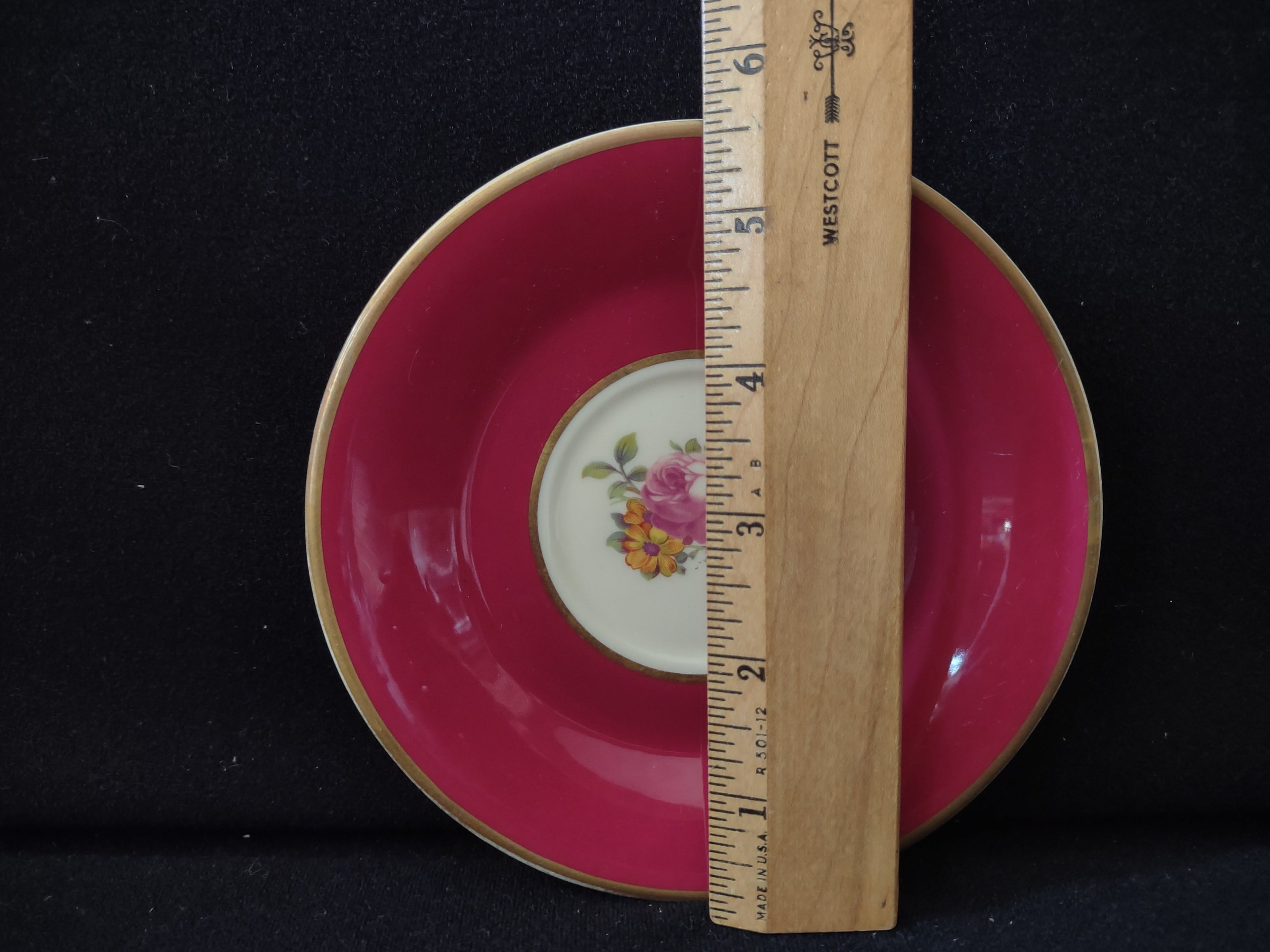Vintage Syracuse China Old Ivory raspberry pink saucer with ruler showing approximately 5.5 inch diameter