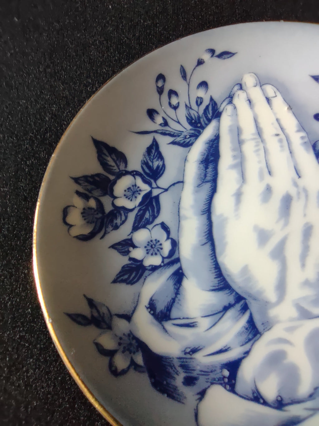 Vintage blue white praying hands plate close-up lower hands and floral detail