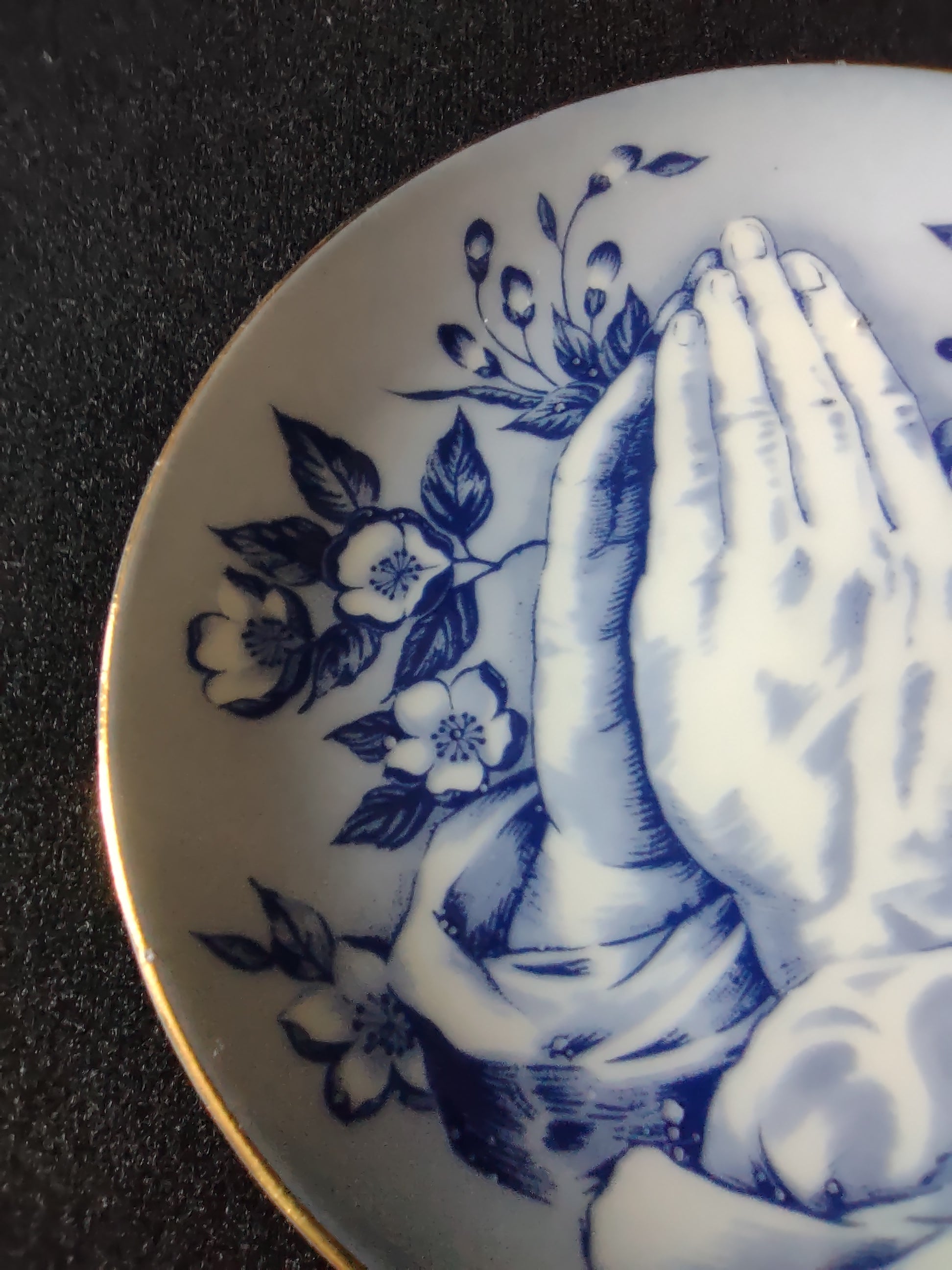 Vintage blue white praying hands plate close-up lower hands and floral detail