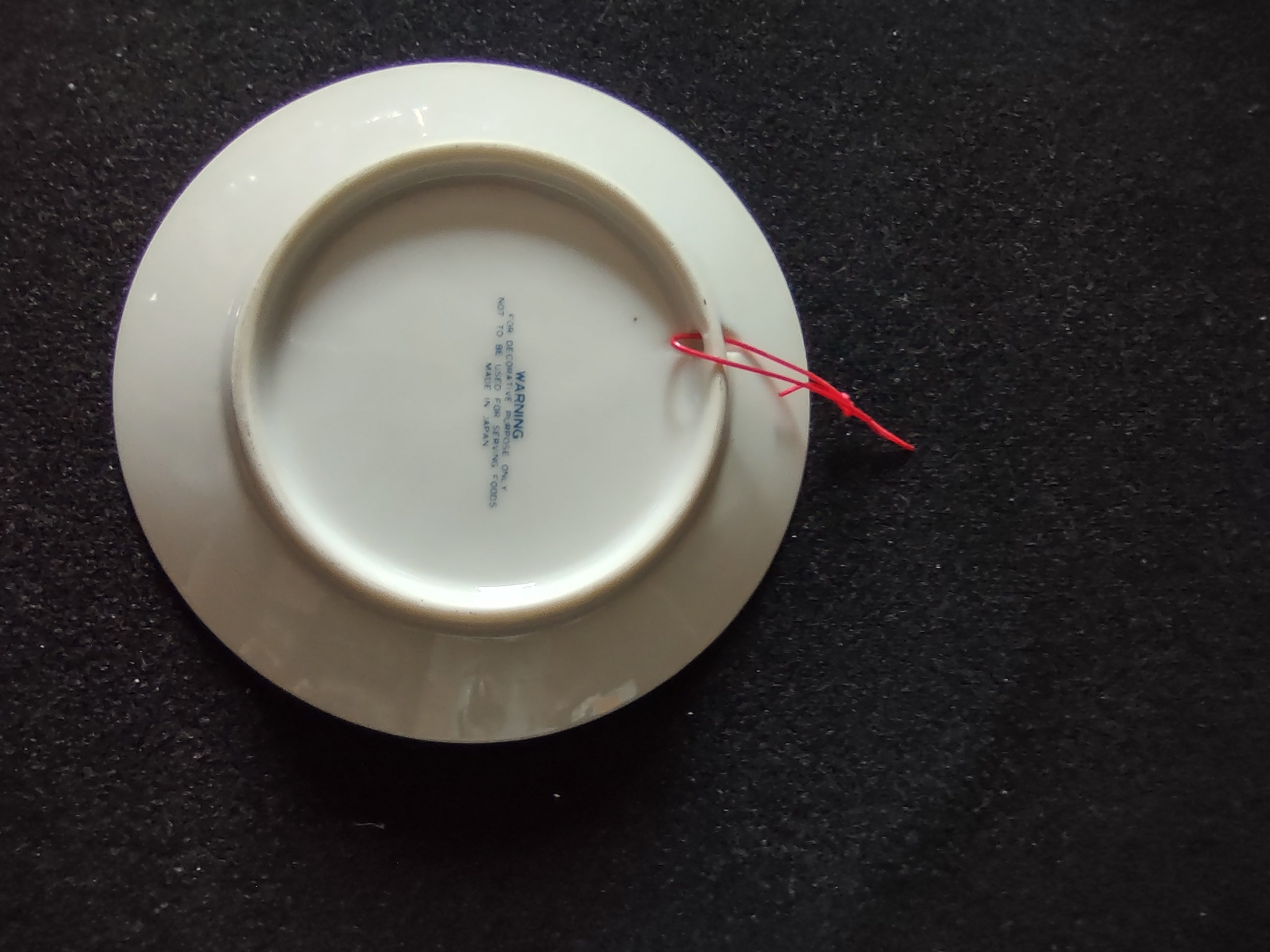 Vintage blue white praying hands plate back view showing maker mark and red cord hanger