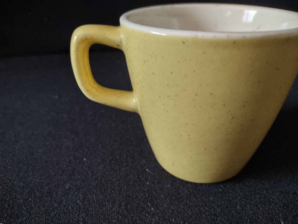 Vintage yellow speckled stoneware coffee cup handle close-up