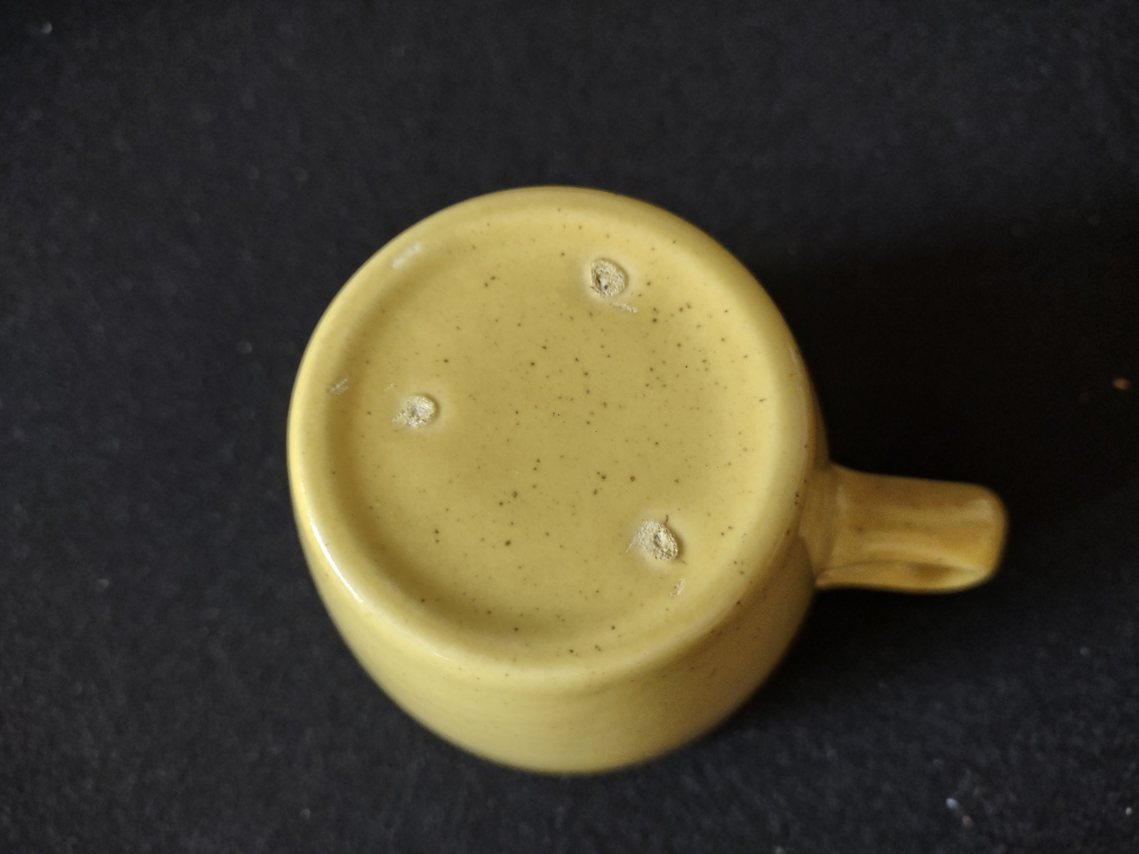 Vintage yellow speckled stoneware coffee cup top view showing white interior