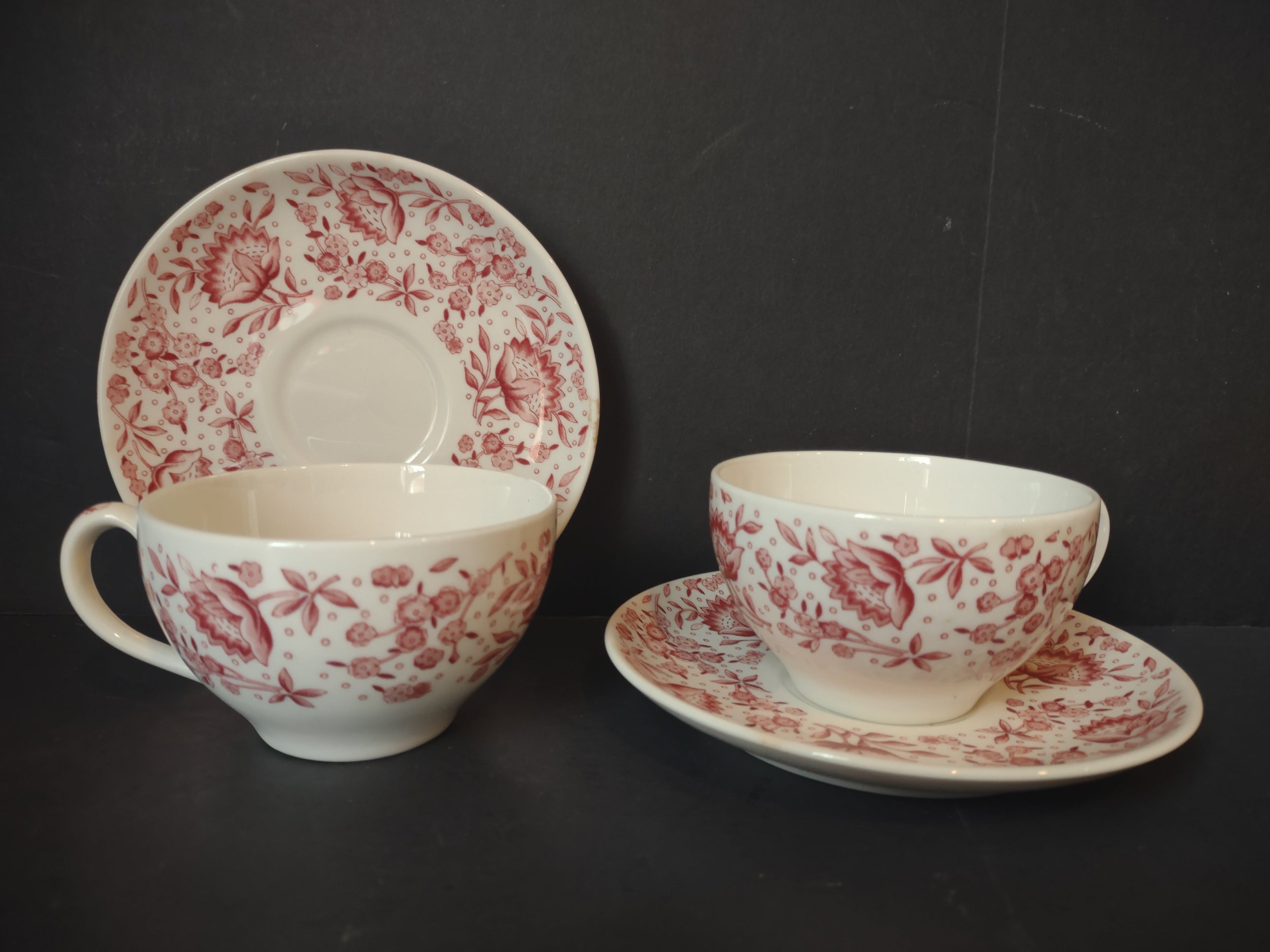 Two Vintage Syracuse China Carefree Mayflower pink floral cup and saucer sets displayed together showing all-over cranberry floral pattern