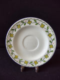 Close-up of Watt Pottery Happy Time pattern showing yellow four-petal flowers and green vine on saucer rim