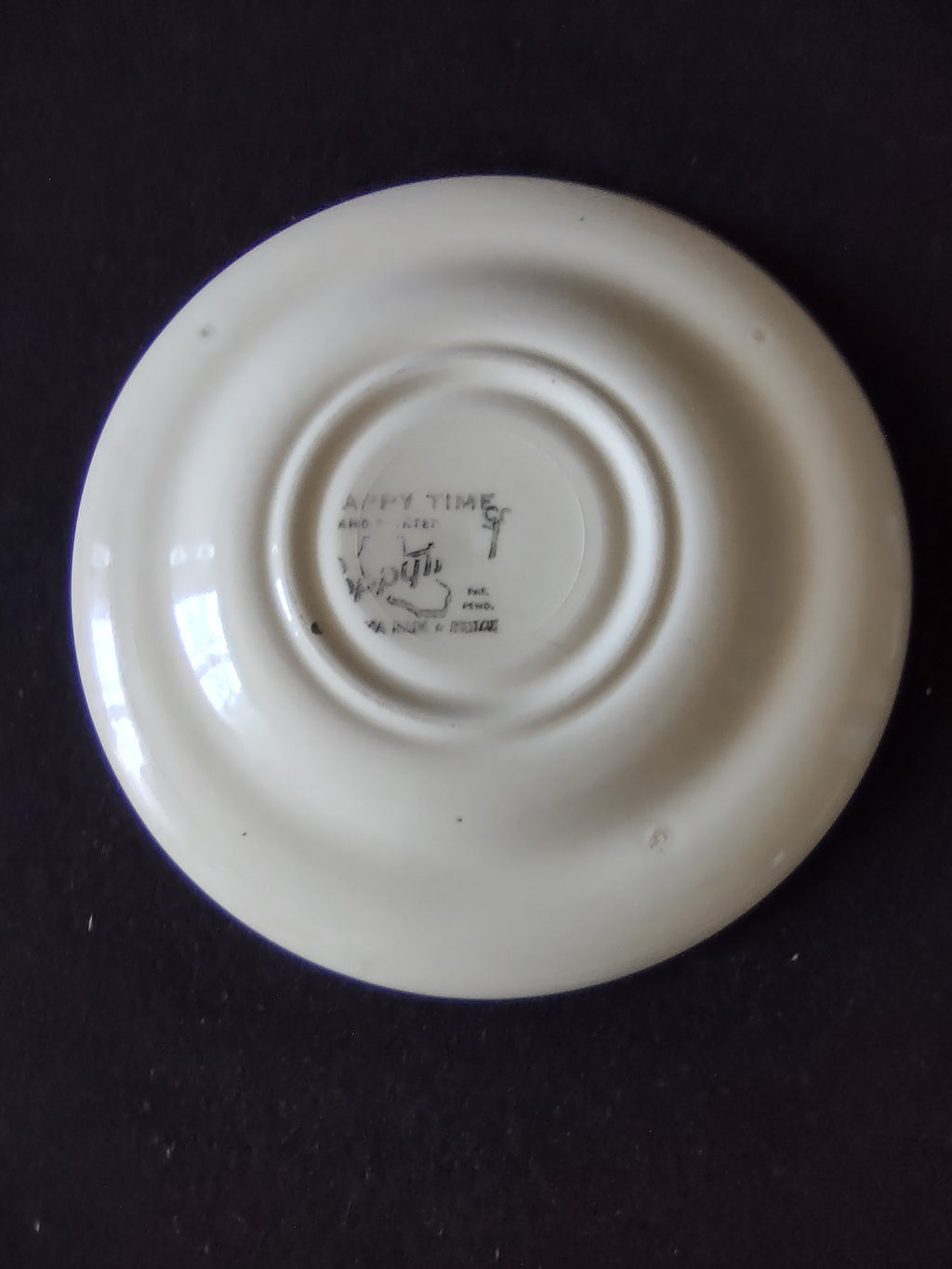 Vintage Watt Pottery Happy Time saucer displayed on easel showing full yellow floral border pattern