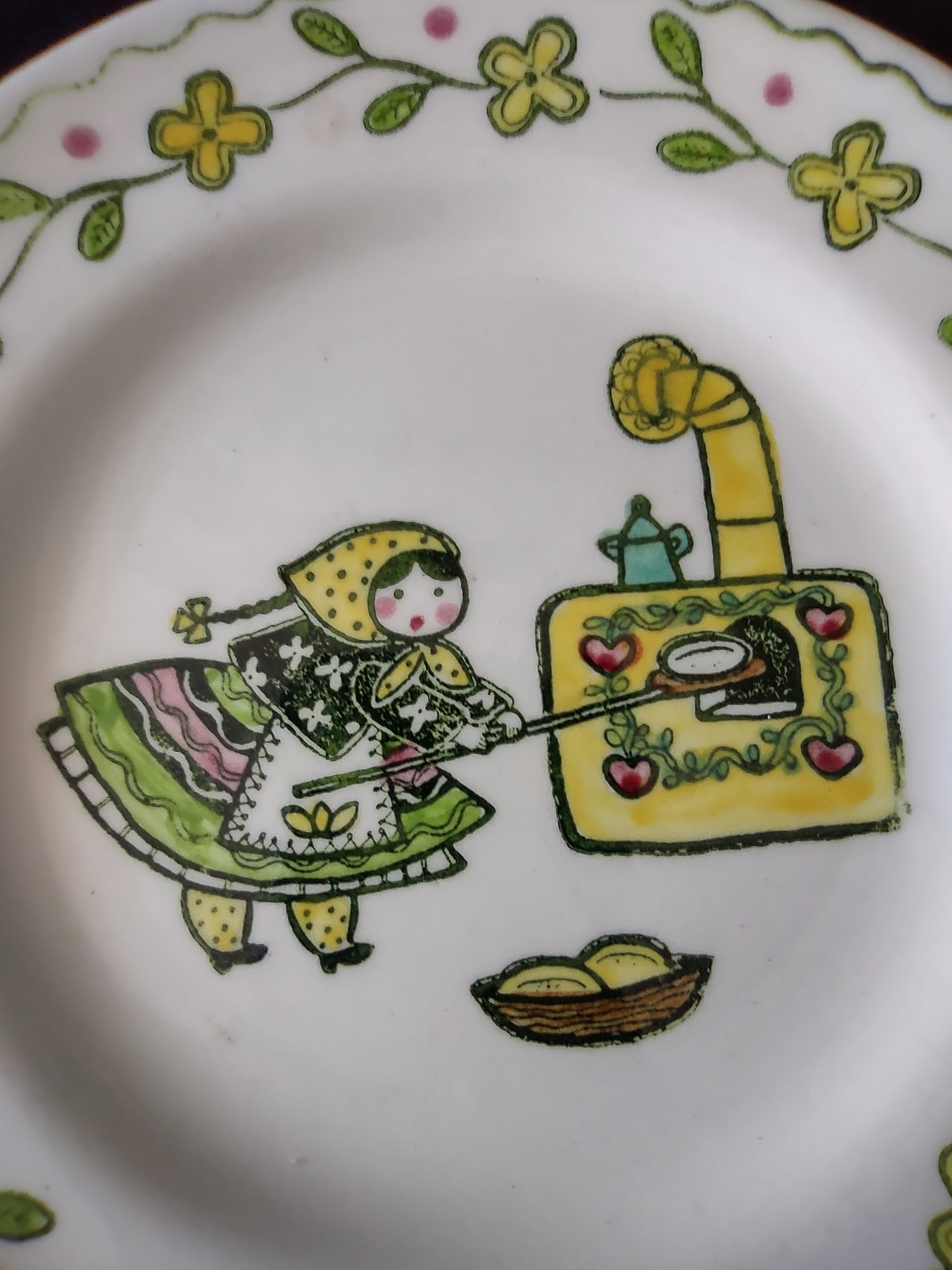 Detail of Metlox Poppytrail Happy Time folk art girl in green dress and yellow bonnet at wood stove