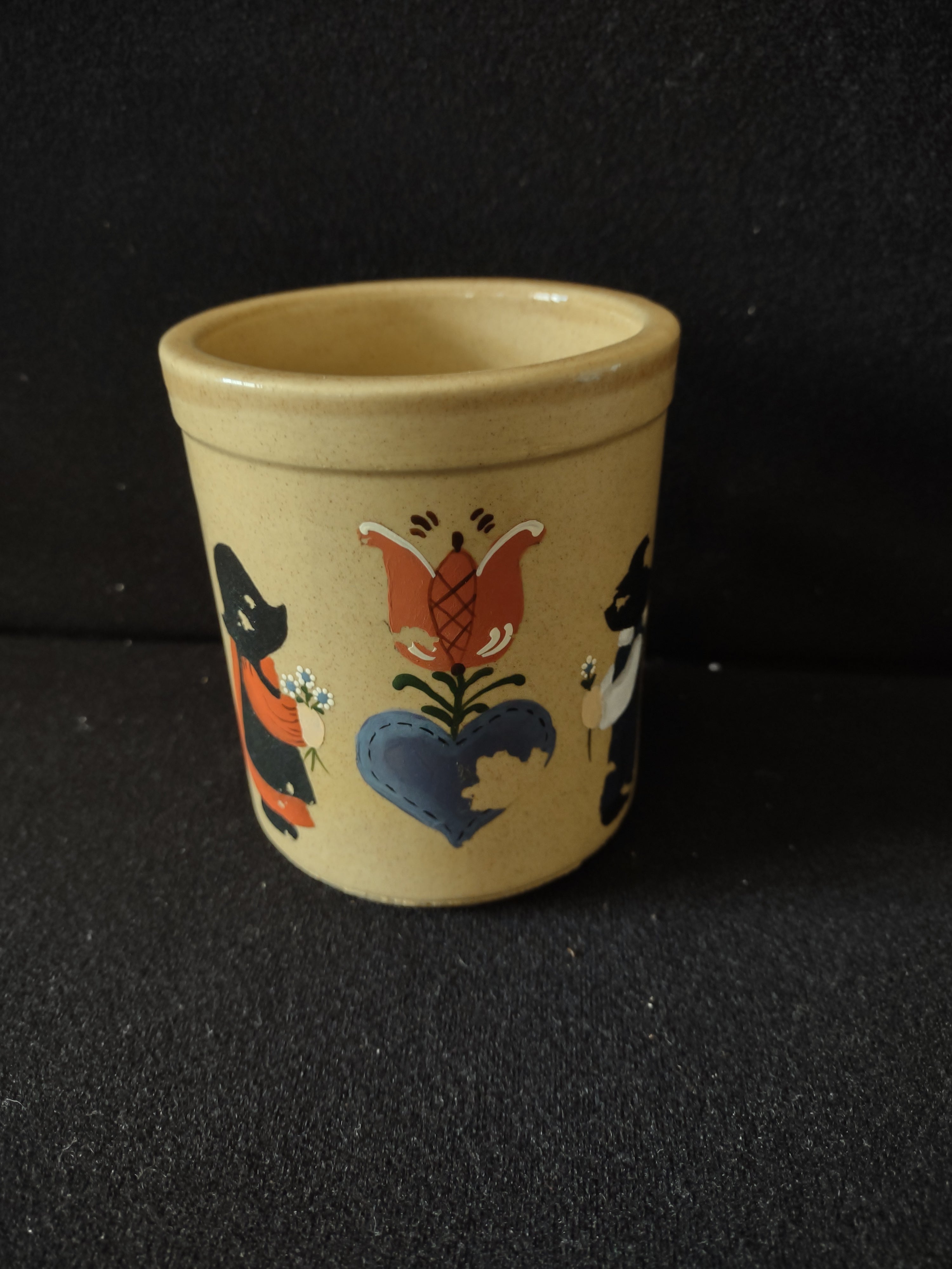 Vintage folk art stoneware crock showing Dutch child figure in black hat and blue clothing holding flower