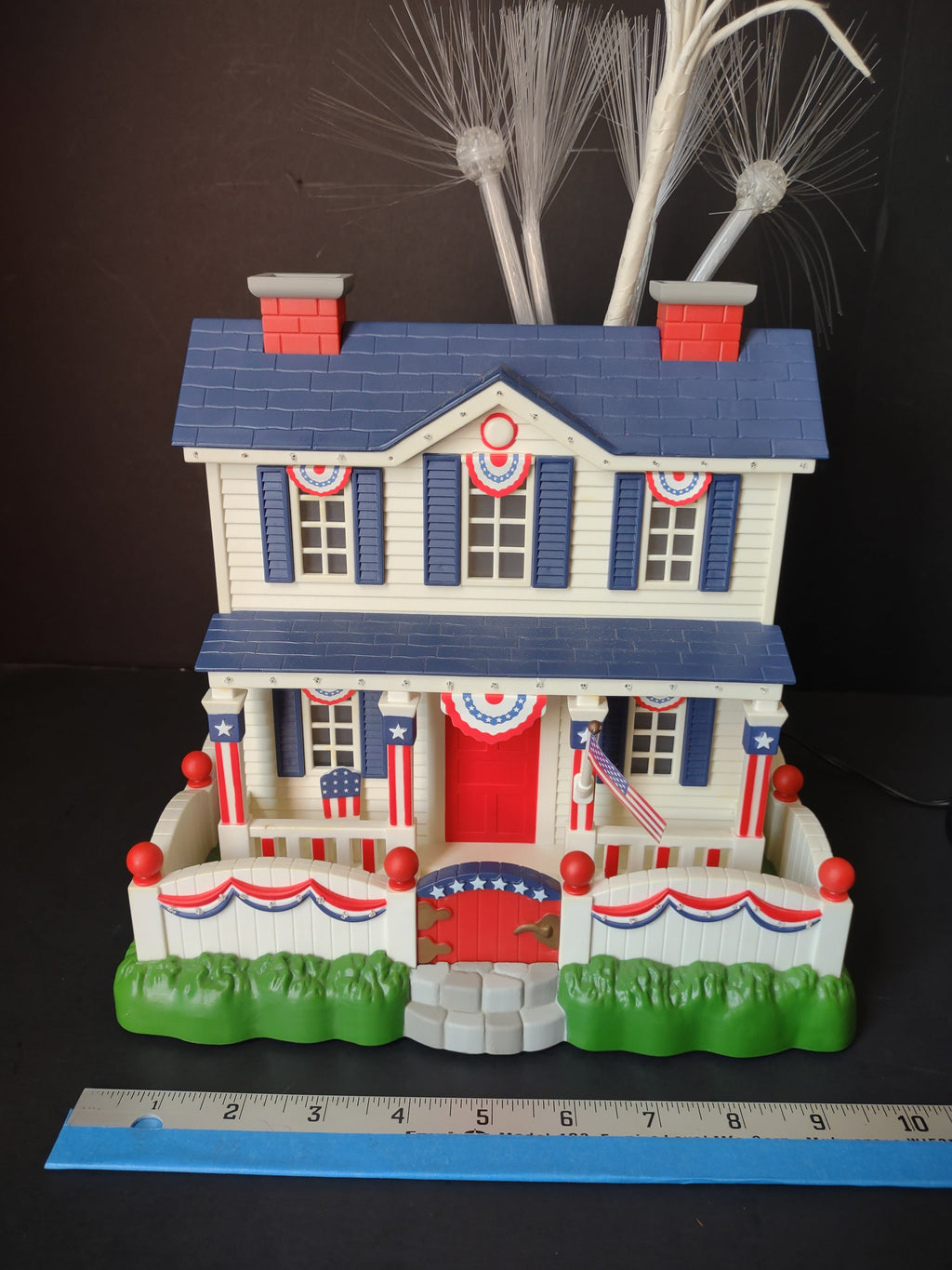 Vintage patriotic fiber optic house figurine decorated in red, white, and blue with American flags and bunting, approximately 8 inches wide