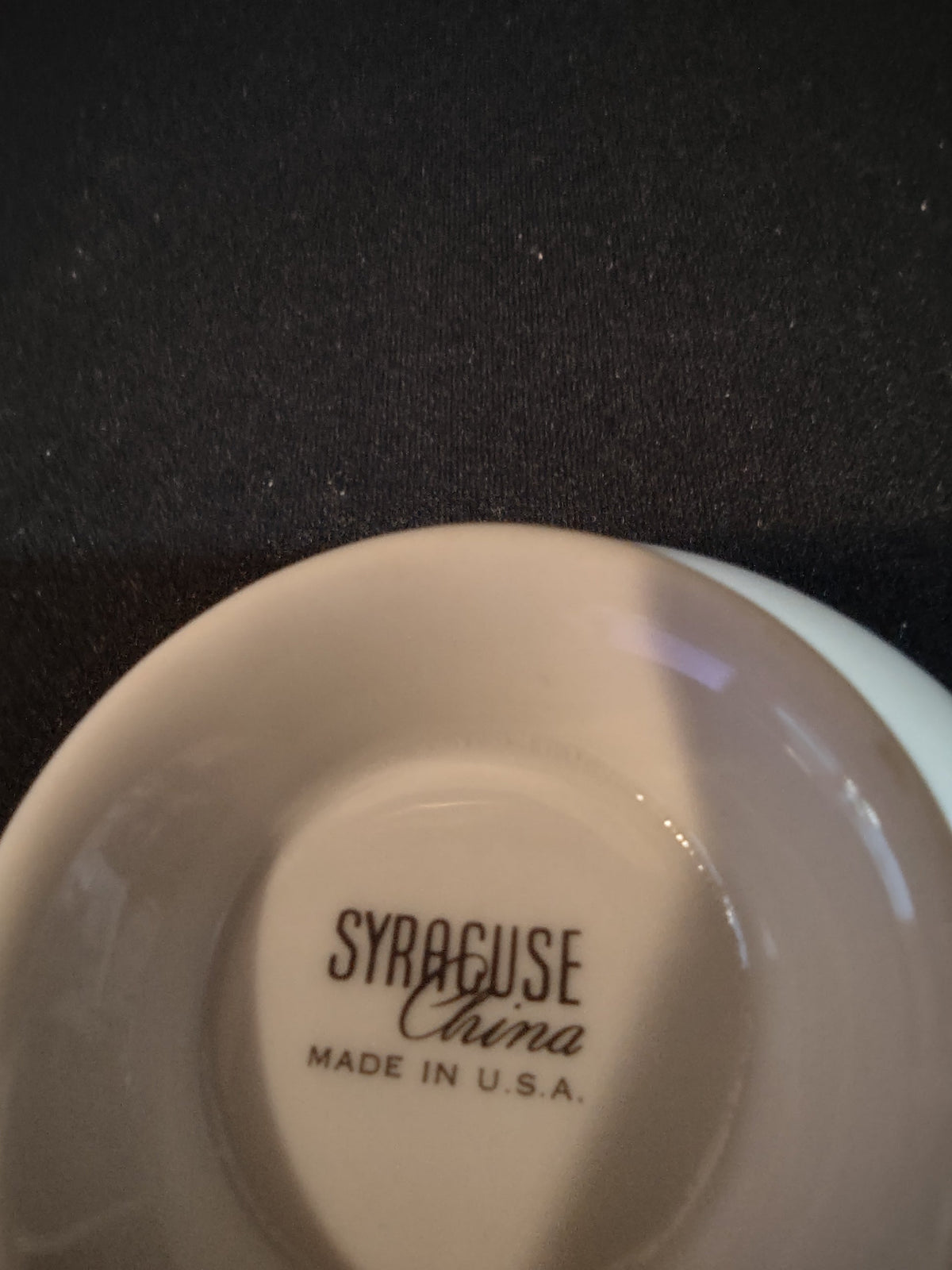 Side view of Syracuse China gold band footed tea cup with ruler