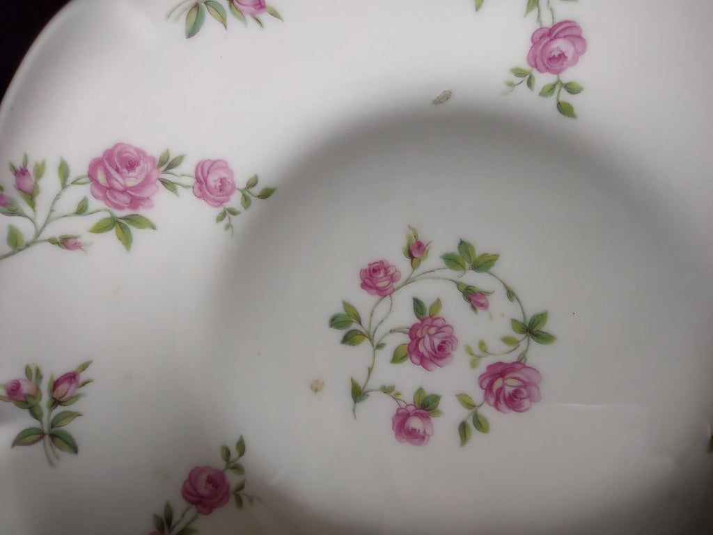 Close-up of Theodore Haviland Delaware bowl rim and well showing scattered pink roses and rosebuds with green foliage, scalloped edge detail