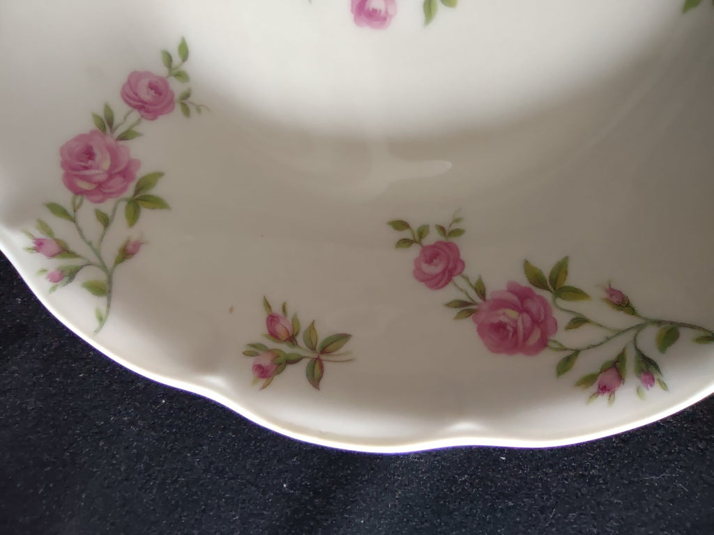 Angled view of Theodore Haviland Delaware scalloped bowl showing full pattern of scattered pink roses and rosebuds on white porcelain