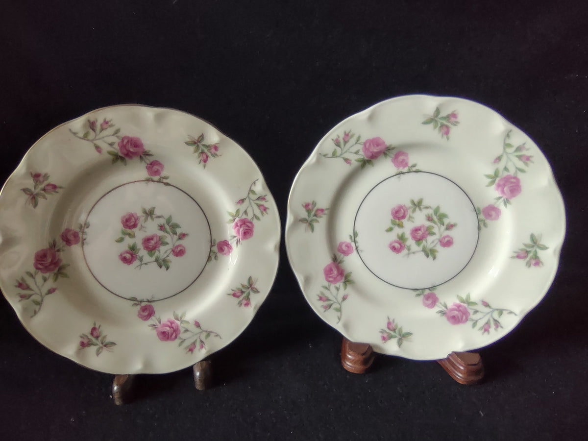 Top view of Theodore Haviland Delaware plate showing central pink rose spray within gold ring, scattered pink rosebuds and roses on rim, scalloped edge