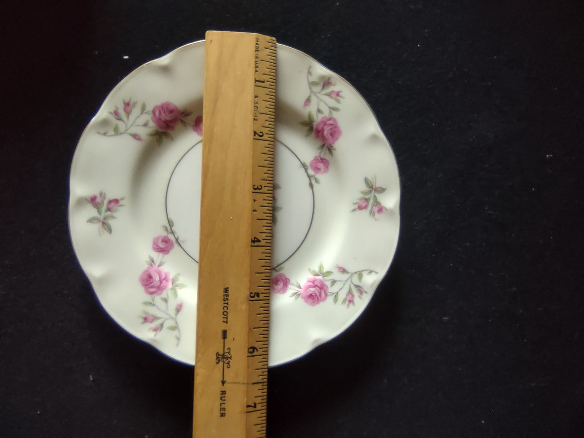 Angled close-up of Theodore Haviland Delaware plate rim showing scattered pink roses and rosebuds with green foliage and gold edge trim