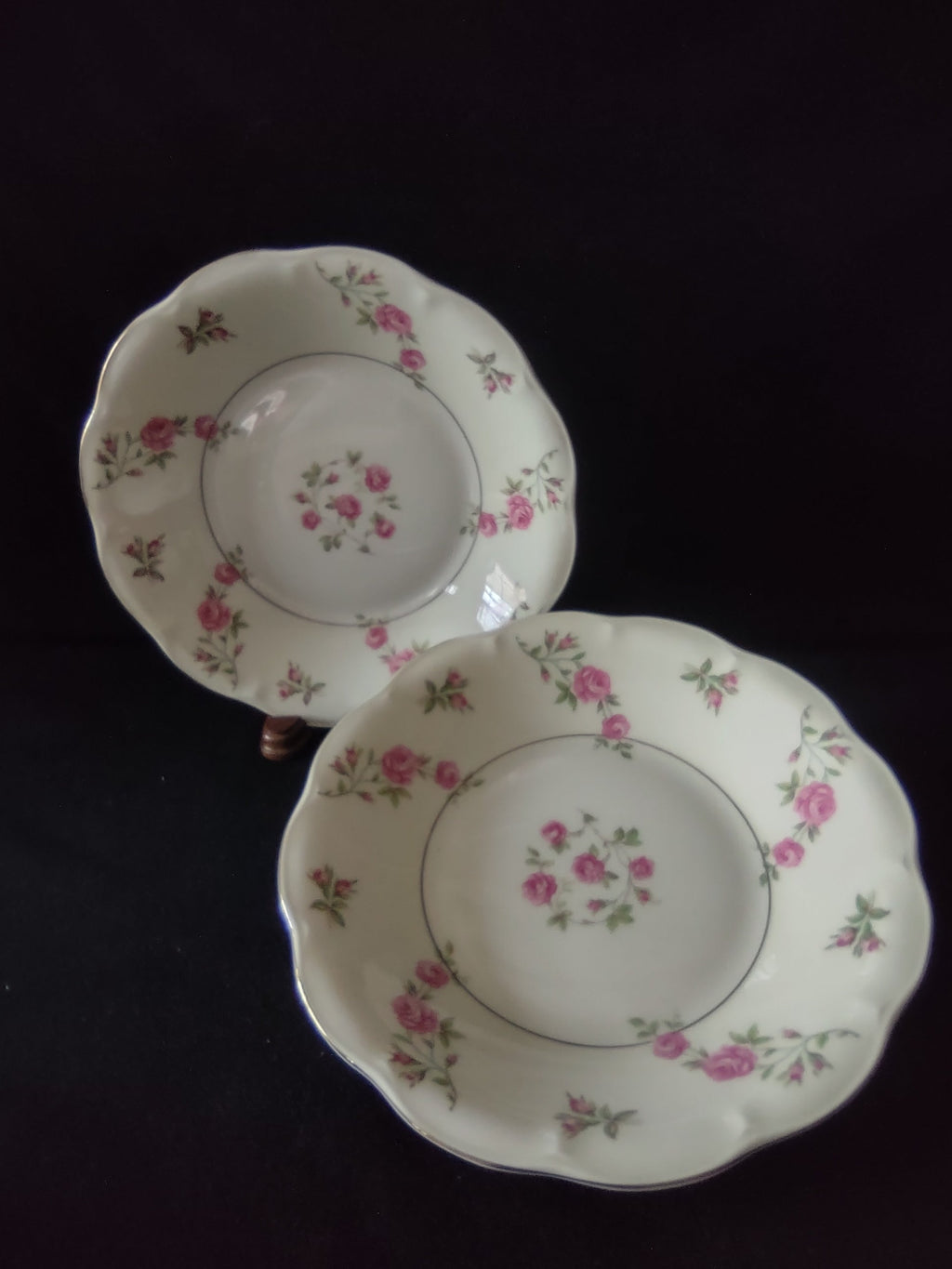 Two Theodore Haviland New York Delaware scalloped plates displayed on plate stands showing scattered pink roses and rosebuds with green foliage on off-white ground