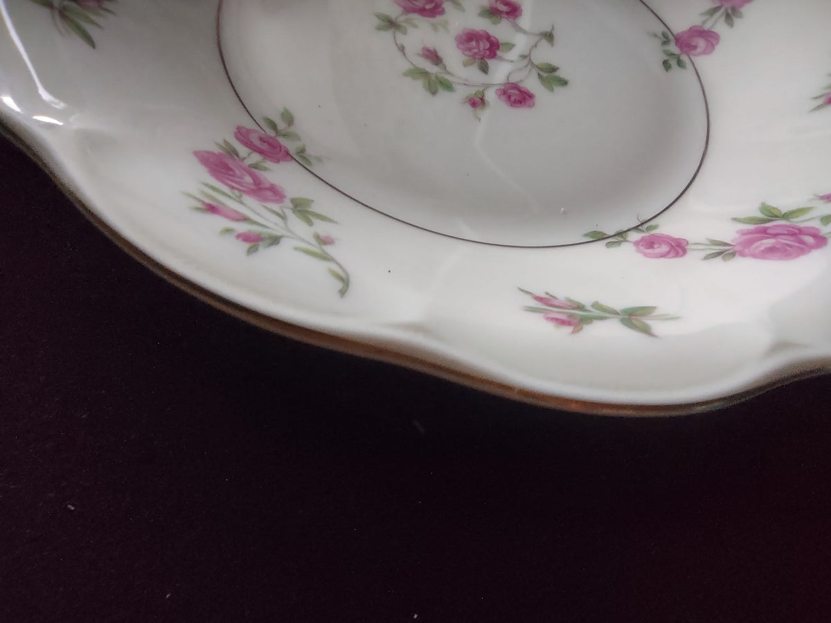 Top view of Theodore Haviland Delaware plate with ruler showing approximately 8 inch diameter, scattered pink roses and rosebuds on off-white ground with scalloped edge