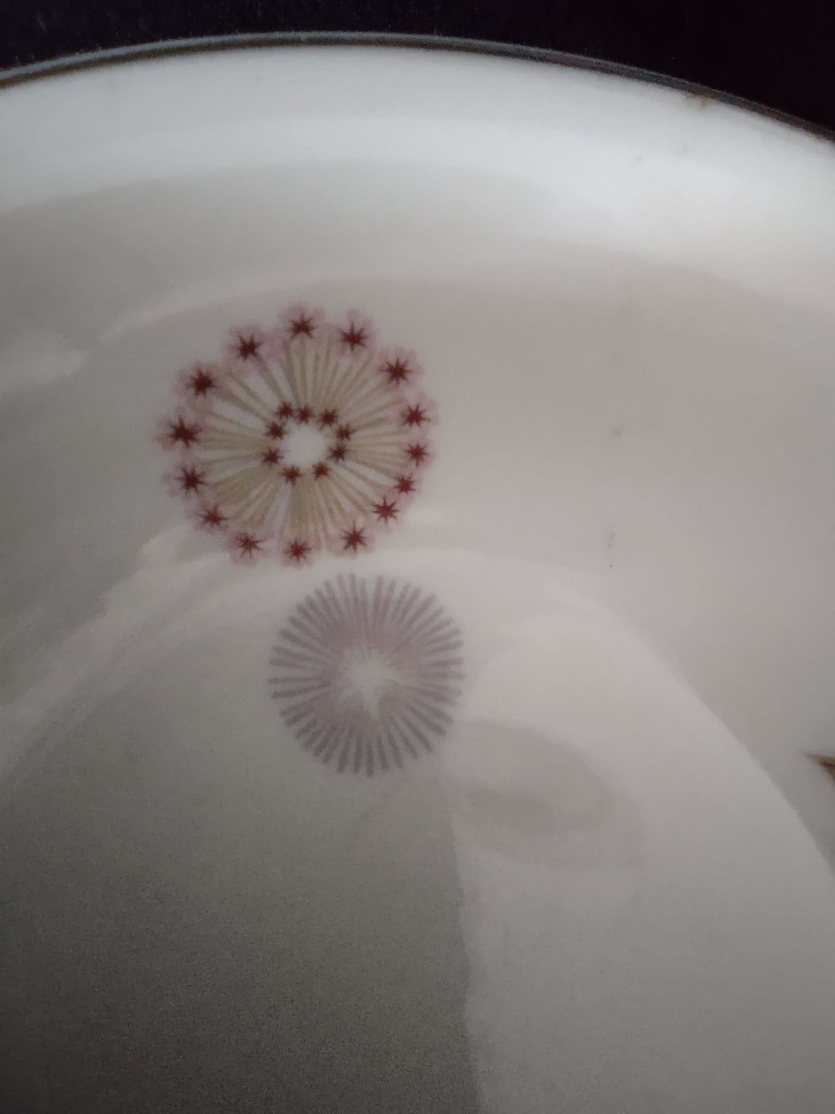 Close-up of Theodore Haviland Meadow Lace saucer showing gold and burgundy starburst medallion with platinum rim trim detail