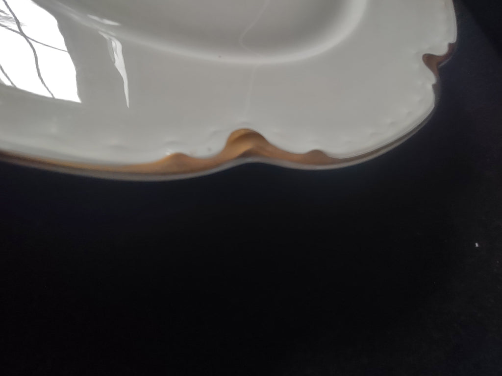 Vintage off-white scalloped gold trim porcelain plate, front view on display stand
