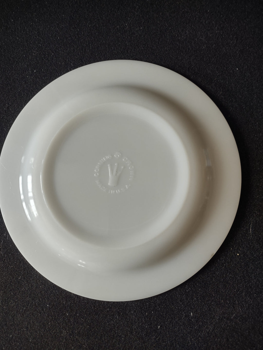 Back of vintage white porcelain plate showing embossed circular maker's mark