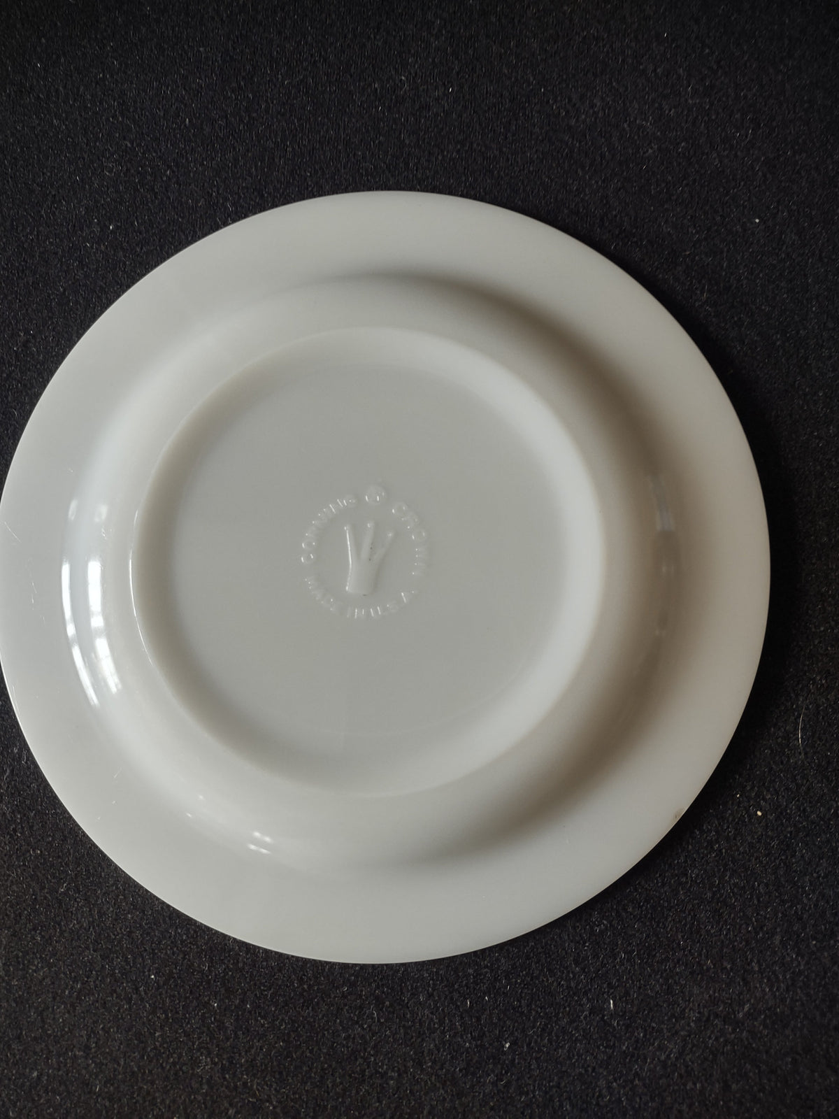 Back of vintage white porcelain plate showing embossed circular maker's mark