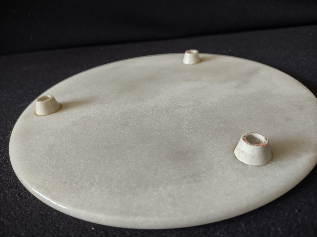White marble round trivet serving board - angled underside view showing rubber feet placement
