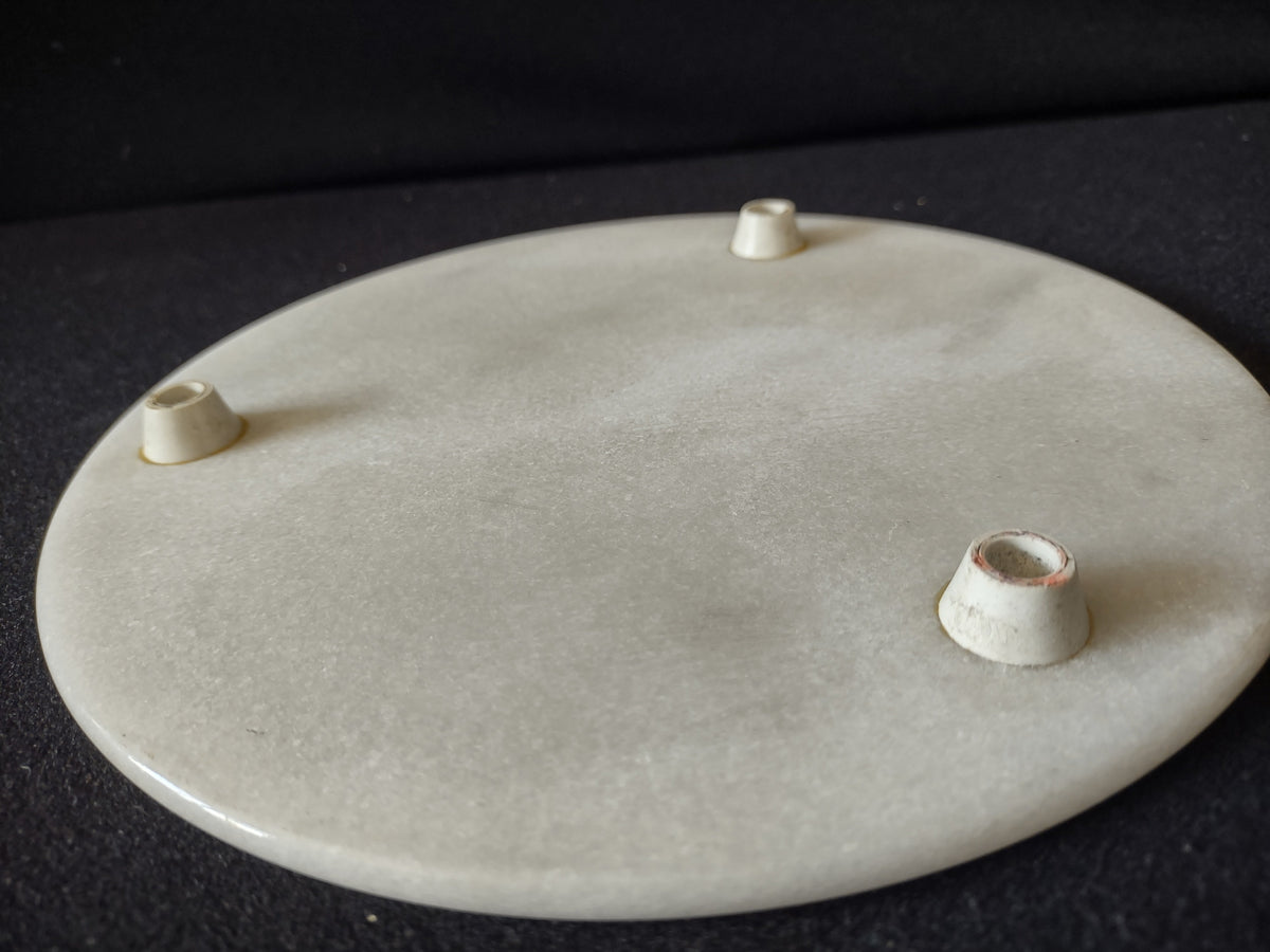 White marble round trivet serving board - angled underside view showing rubber feet placement