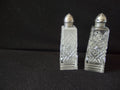 Vintage mismatched pressed glass salt and pepper shakers with silver dome lids next to ruler showing approximately 4 inch height
