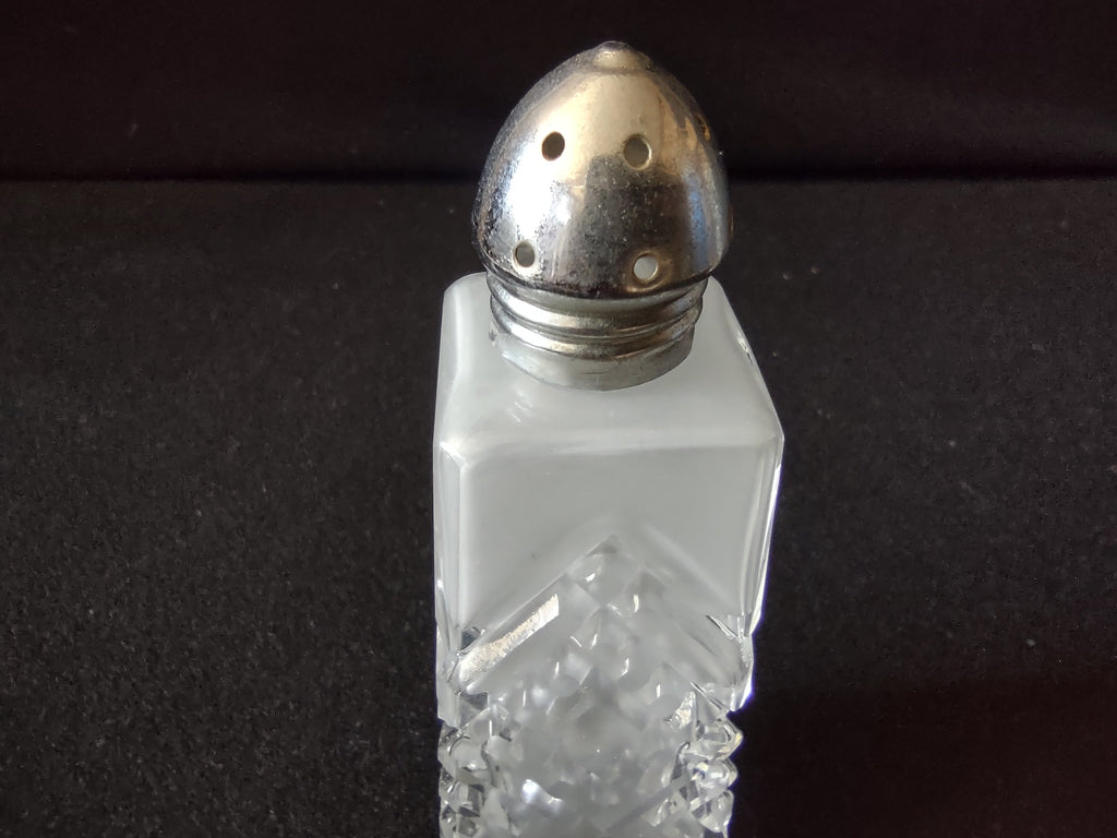 Close-up of vintage pressed glass salt shaker dome lid with tarnished silver-tone metal